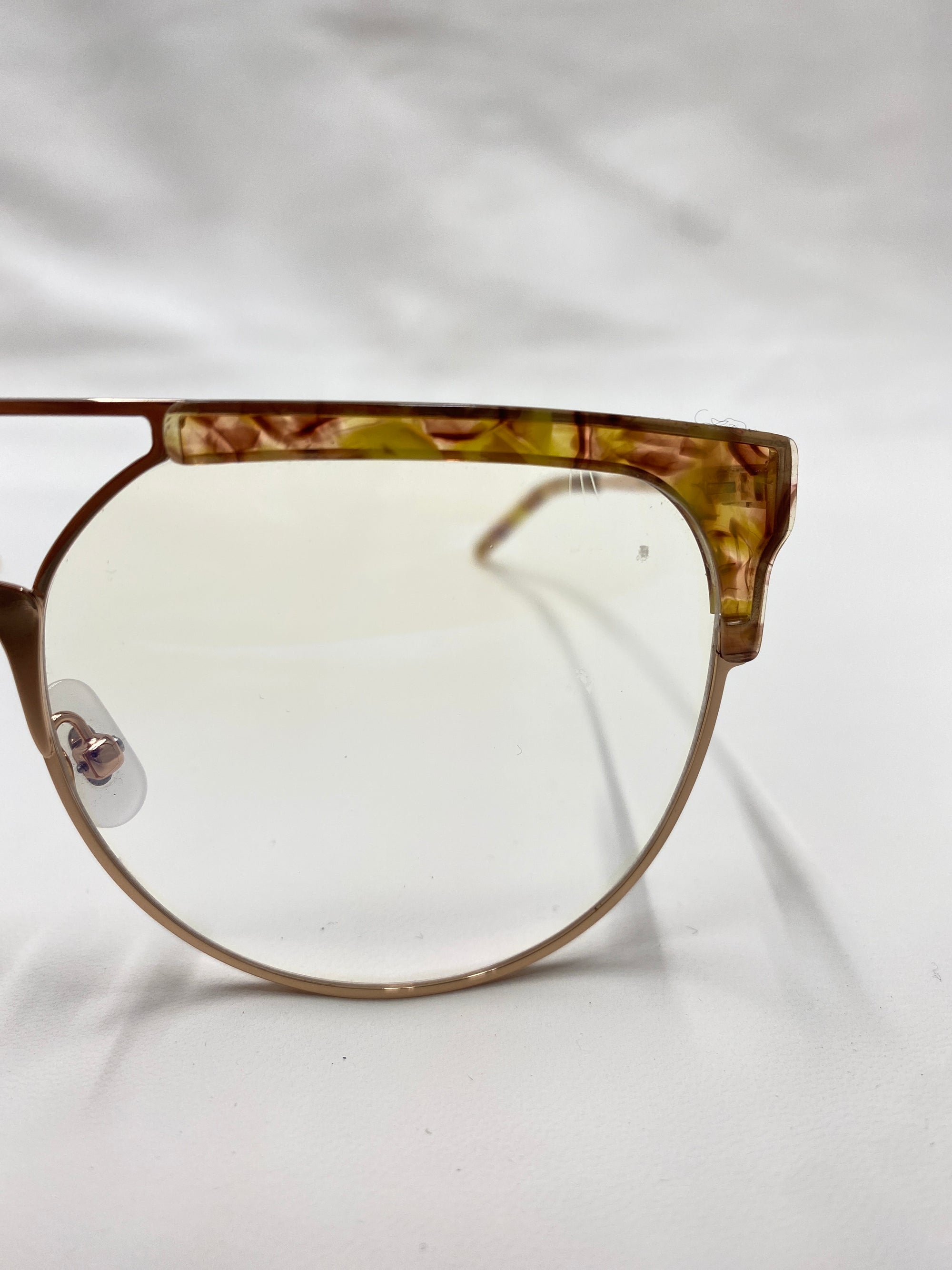 Close-up of the right half of a pair of fashion-forward glasses known as Frosty by For Art&#39;s Sake®. The frame boasts a unique design, blending transparent brown and yellow tortoiseshell along the top edge, transitioning into an electric green marble acetate structure for a chic and modern look.