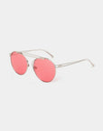 A pair of sunglasses from For Art's Sake® featuring thin, stainless steel frames and round, pink-tinted nylon lenses. The design boasts a minimalistic aesthetic with slender arms and a delicate nose bridge, set against a white background.