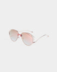 A pair of For Art's Sake® Dark Eyes aviator-style sunglasses with light pink-tinted lenses and rose gold stainless steel frames. The sunglasses have a sleek, minimalist design and thin arms, offering 100% UV protection while resting on a white background.