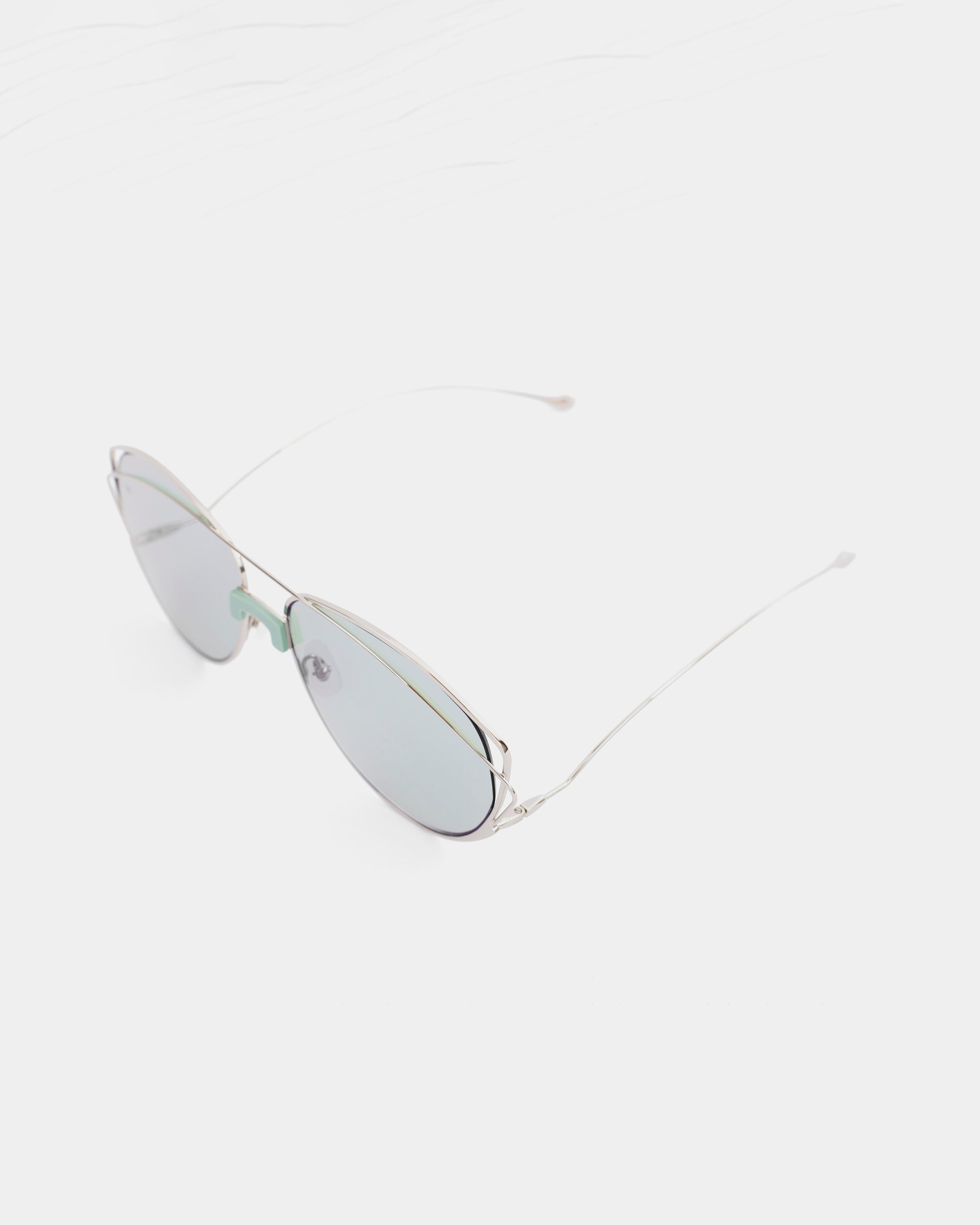 A pair of stylish, reflective Dark Eyes sunglasses from For Art&#39;s Sake® with thin stainless steel frames and lightly tinted nylon lenses offering UV protection is displayed against a plain white background. The design is minimalist and sleek.