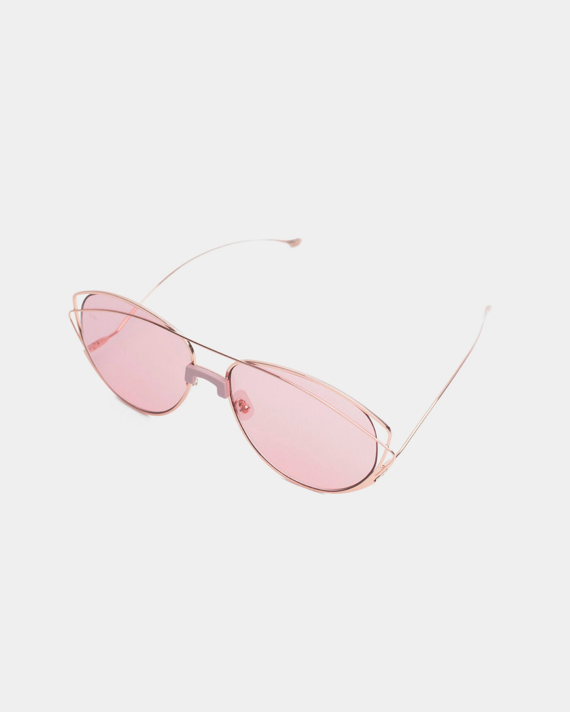 A pair of For Art&#39;s Sake® Dark Eyes sunglasses with pink-tinted, nylon lenses and thin, rose gold frames offering 100% UV protection, laid on a white background.