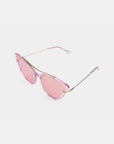 The T Two sunglasses by For Art's Sake® are a stylish pair of pink-tinted cat-eye glasses featuring thin gold arms and an acetate frame. The lenses provide 100% UV protection, seamlessly matching the pink-hued frame. The exaggerated cat-eye lens design blends retro charm with modern elegance, all showcased against a plain white background.