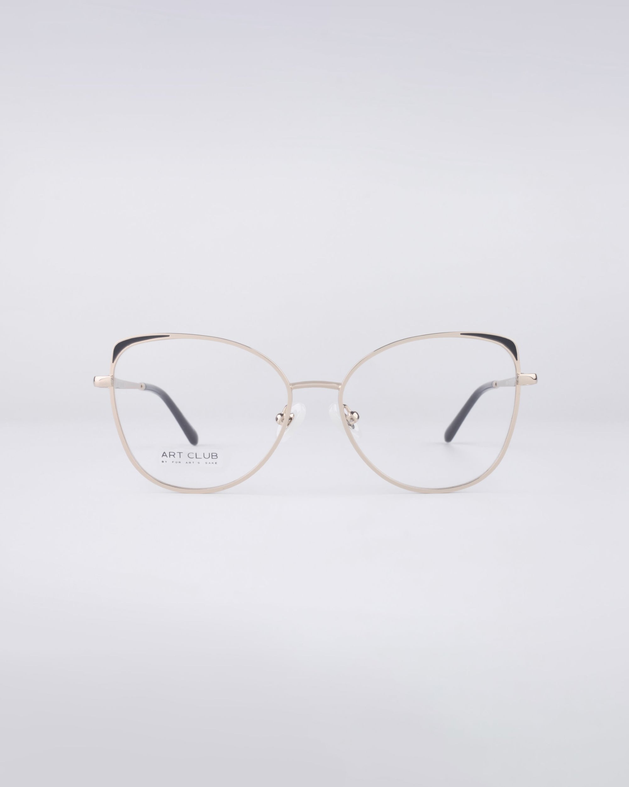 A pair of contemporary Ada frames from For Art's Sake® with a stainless steel core is positioned on a simple white background. The round, metallic eyeglasses are equipped with transparent blue light filter lenses, complemented by dark temples and adorned with a discreet brand logo on the lens.