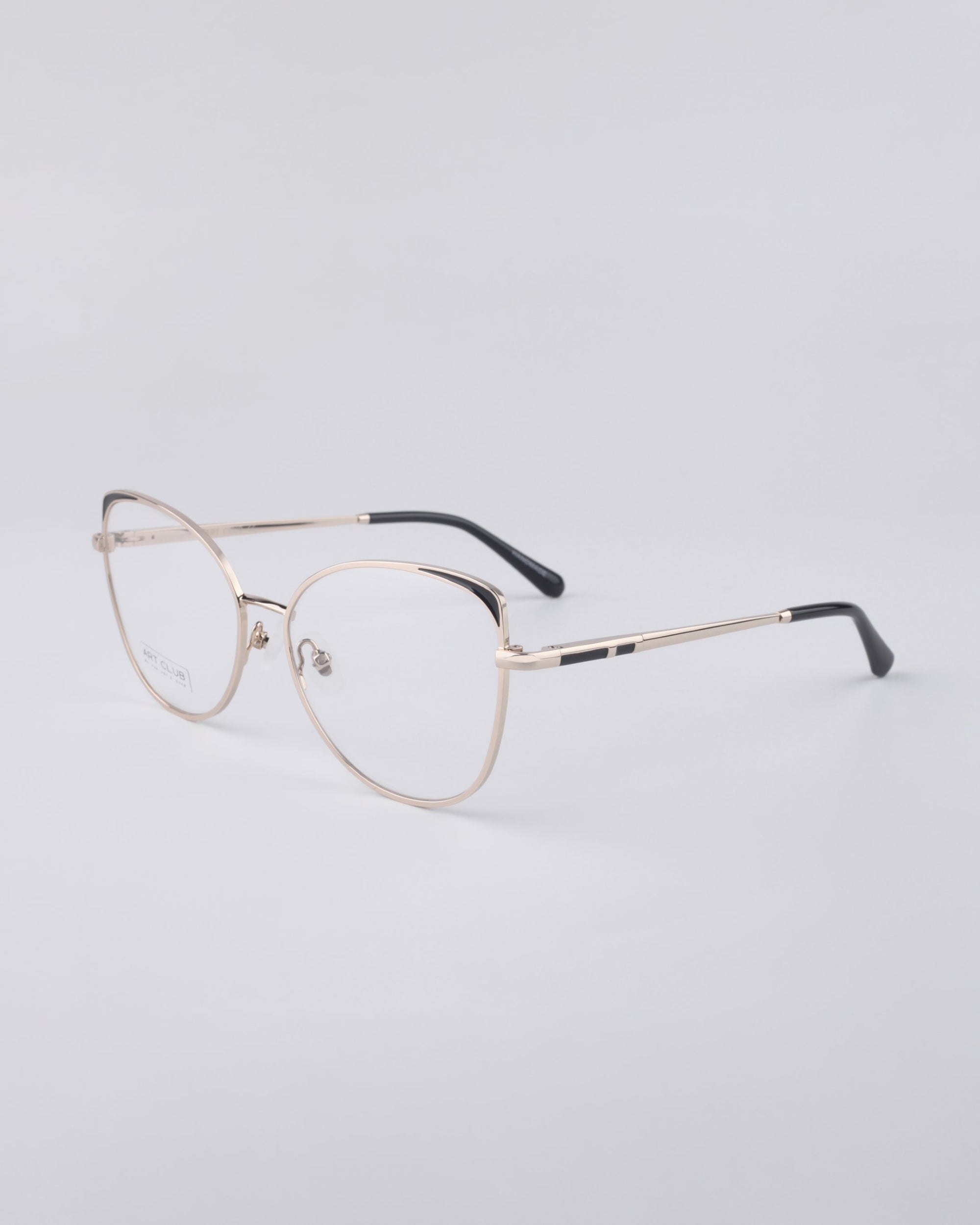 A pair of sleek For Art's Sake® Ada frames with thin, round lenses and black temple tips rests on a smooth, light gray surface. Featuring a stainless steel core, these glasses boast a minimalist and modern design.