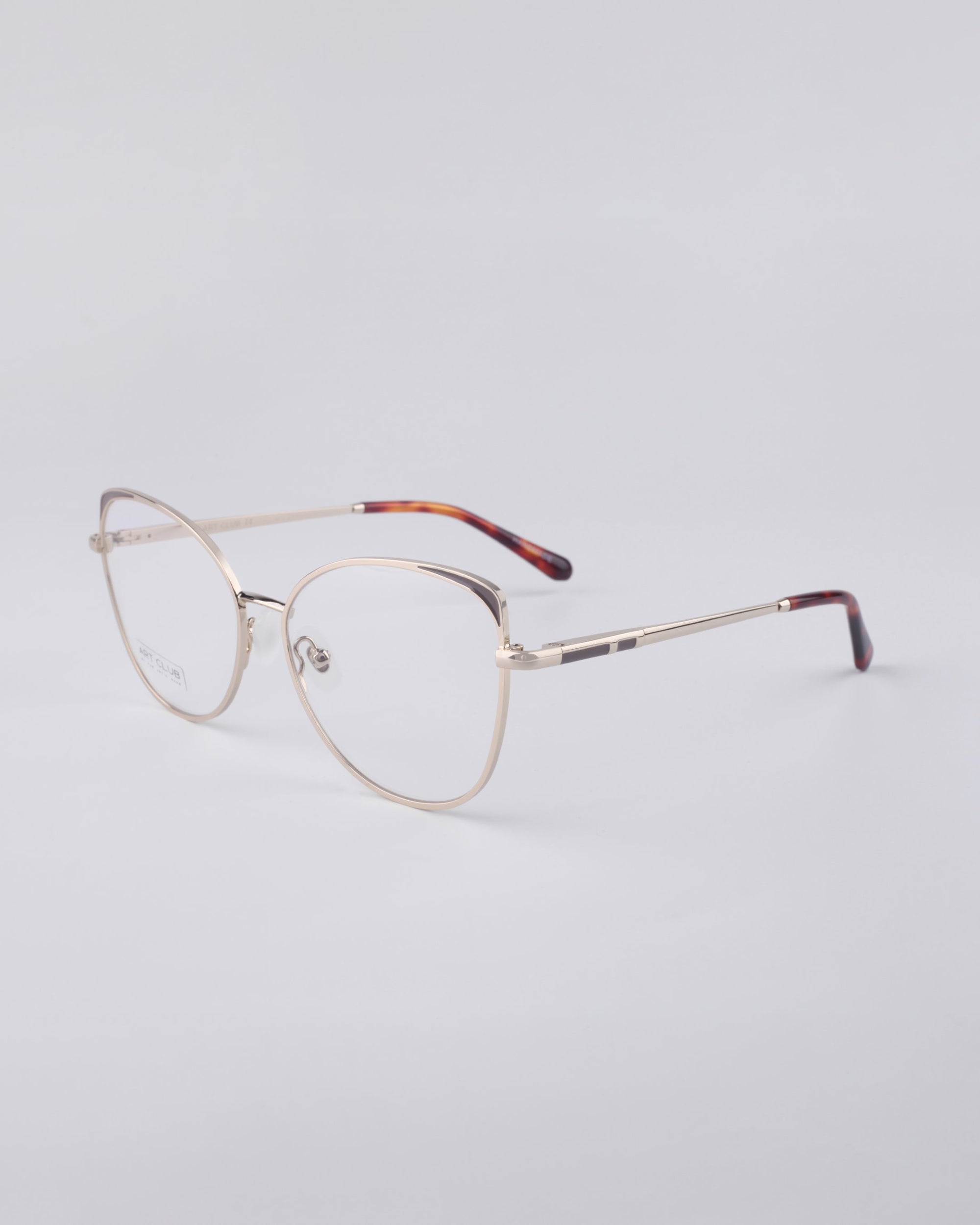 Displayed against a plain white background, the Ada frames from For Art's Sake® showcase chic eyeglasses with a stainless steel core and sleek metal frames. The glasses feature brown-tinted, tortoiseshell-patterned temple tips, while the lenses offer a blue light filter for added protection.