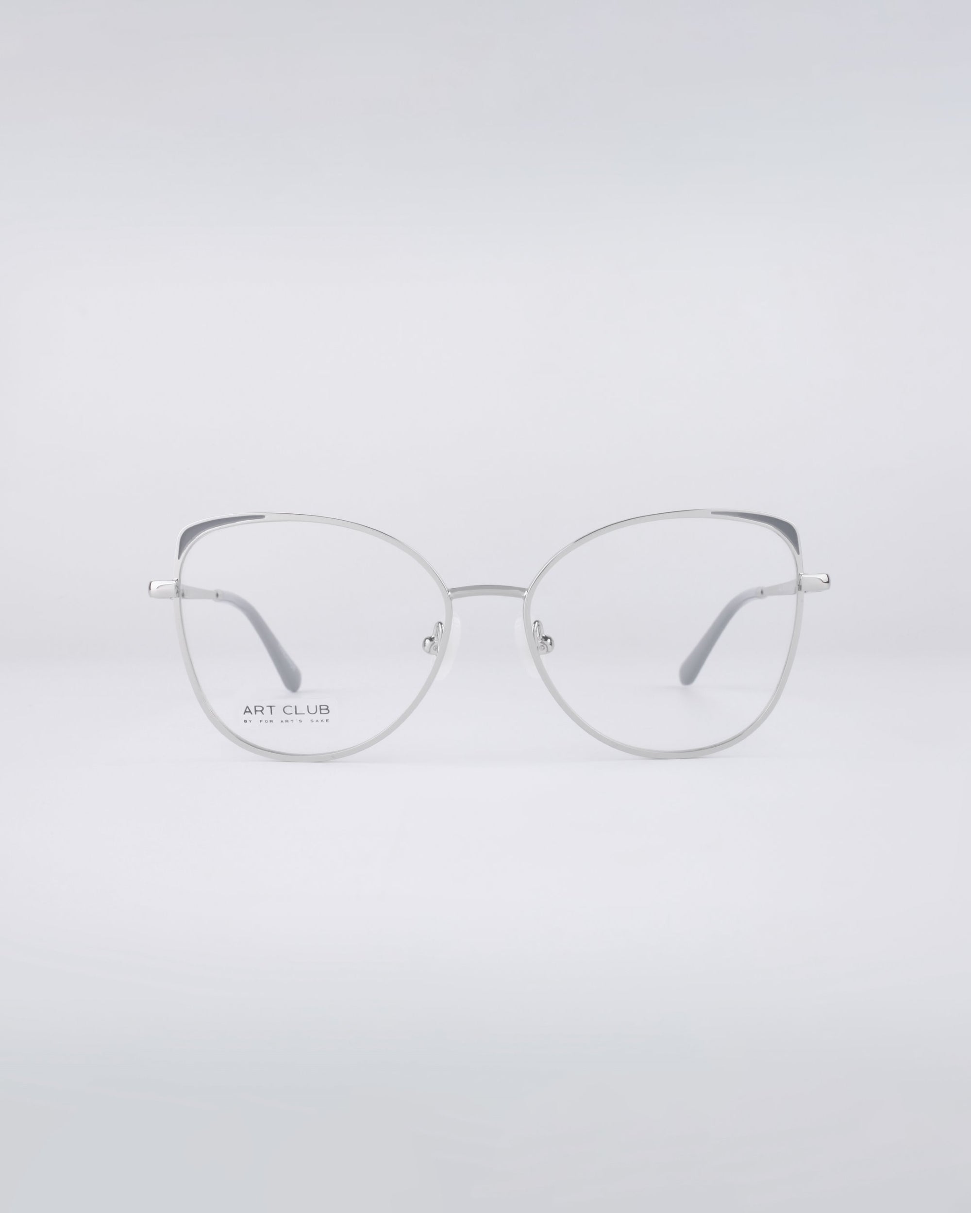 Centered against a plain white background is a pair of Ada frames from For Art's Sake®, featuring sleek silver rims and clear lenses. With their modern, minimalist design and stainless steel core, these eyeglasses include subtle branding on the left lens and offer an option for blue light filter lenses.