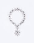 The Crescent Moon Bracelet by For Art's Sake® is a silver chain bracelet with a circular toggle clasp, featuring a sun-shaped charm that hangs elegantly. The charm's rays and polished surface exude an elegant charisma. With a 20cm length, this exquisite piece is beautifully set against a simple, light grey background.