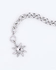 A bracelet from For Art's Sake® showcases a sun charm, set on a light background, featuring an ornamental chain design.