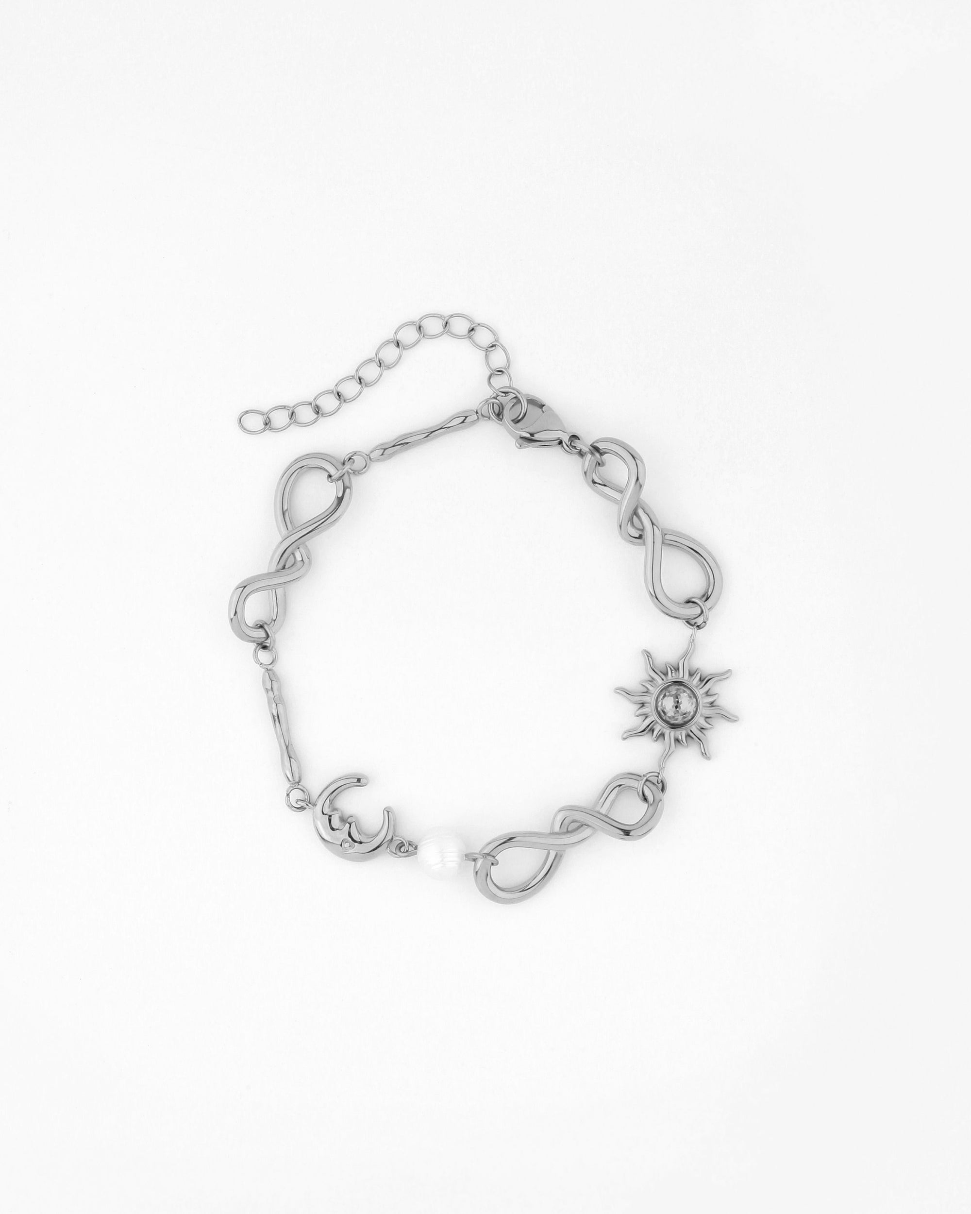 The Sloane Bracelet by For Art&#39;s Sake® is a silver piece featuring intertwined infinity symbols, a central sun-shaped charm adorned with a star design, a crescent moon charm, and a white bead. The bracelet comes with an adjustable extension chain and a lobster clasp closure, blending elegance and celestial beauty.