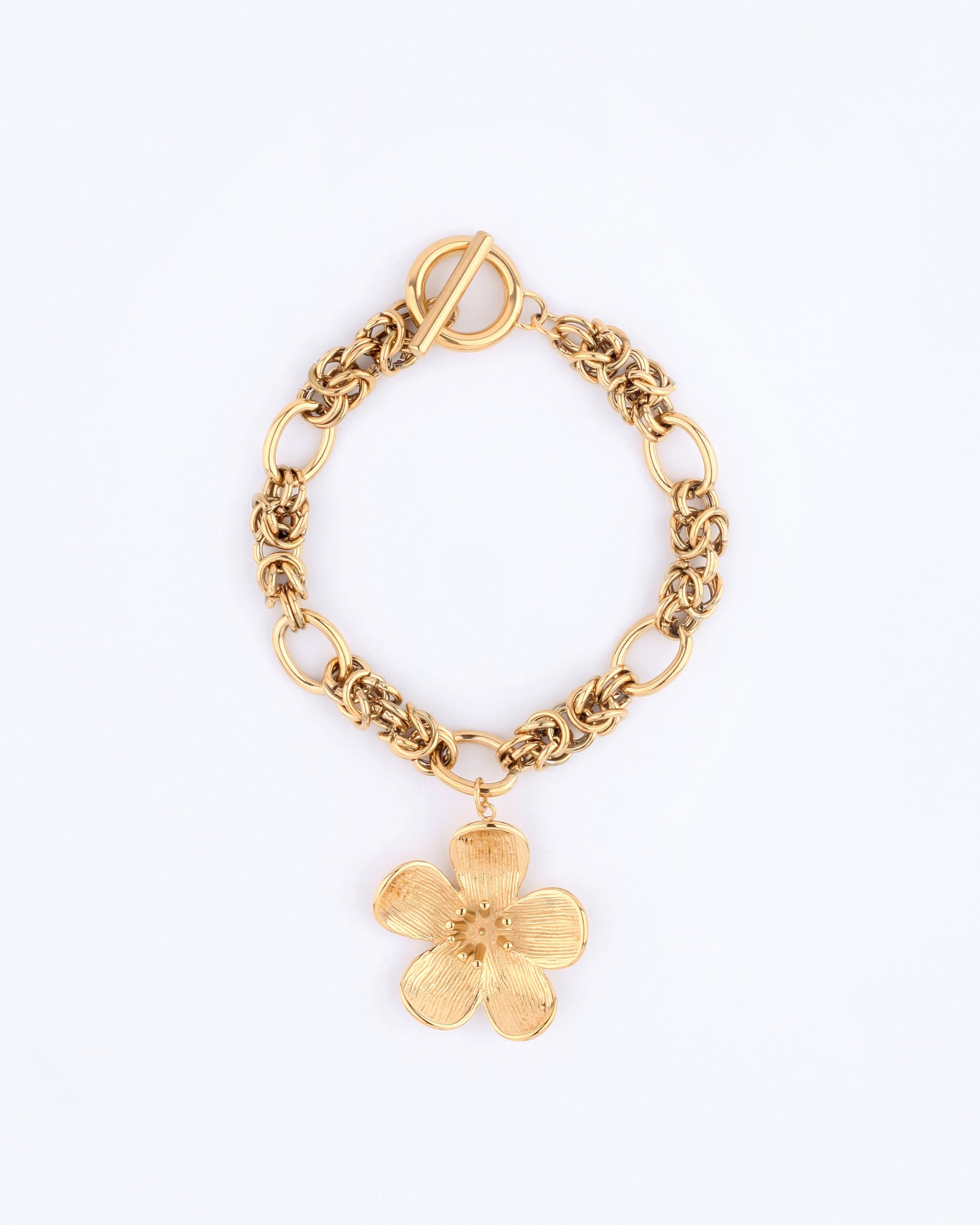 The Blossom Bracelet from For Art's Sake® is a gold chain bracelet with intricate links, highlighted by a large flower pendant. It elegantly wraps around the wrist and features a toggle clasp, lying gracefully on a plain light background.