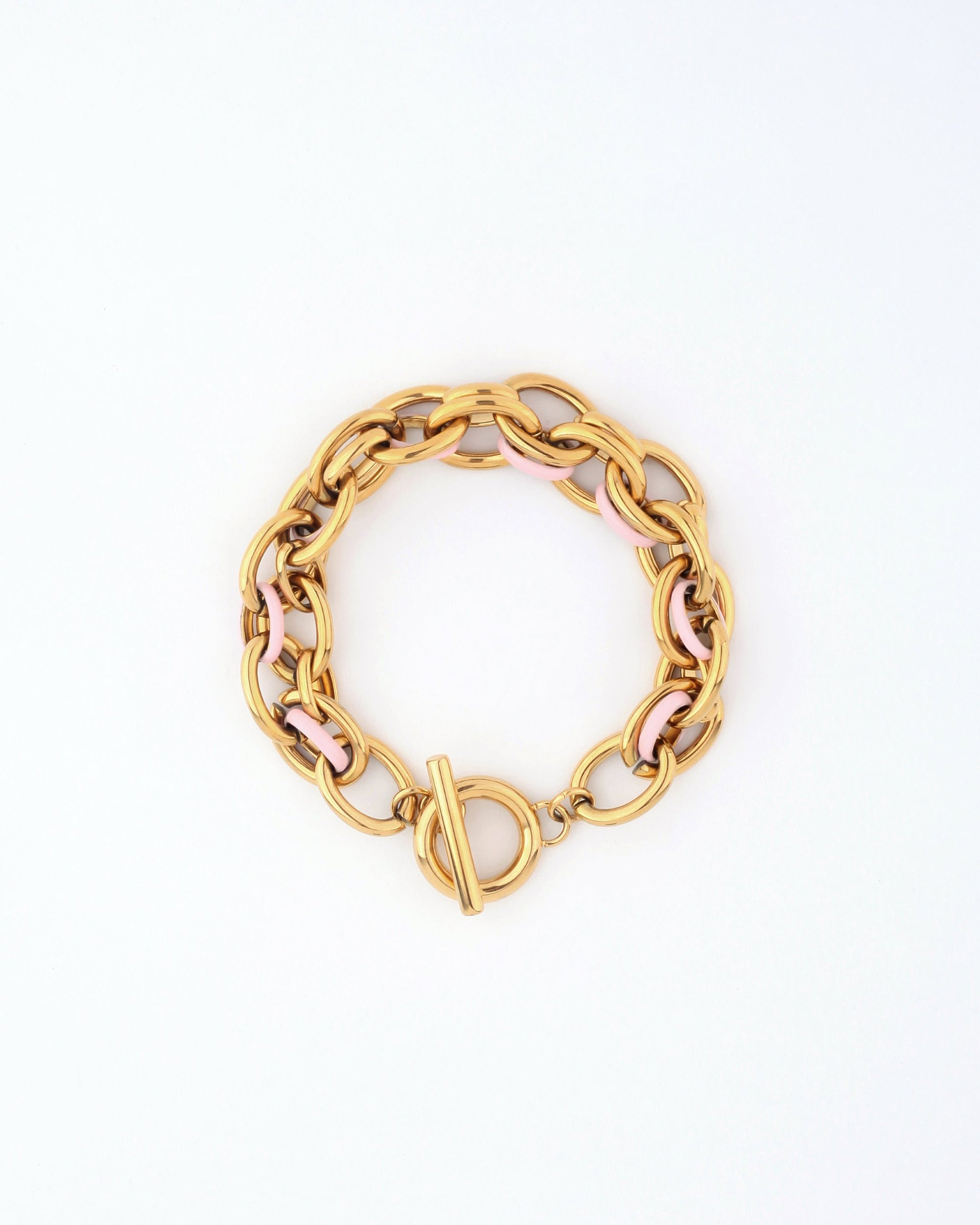 The Raya Bracelet by For Art's Sake® showcases an elegant gold chain with a toggle clasp, featuring alternating gold and light pink links beautifully arranged in a circle on a white background. Its meticulous design guarantees the perfect fit for any wrist.