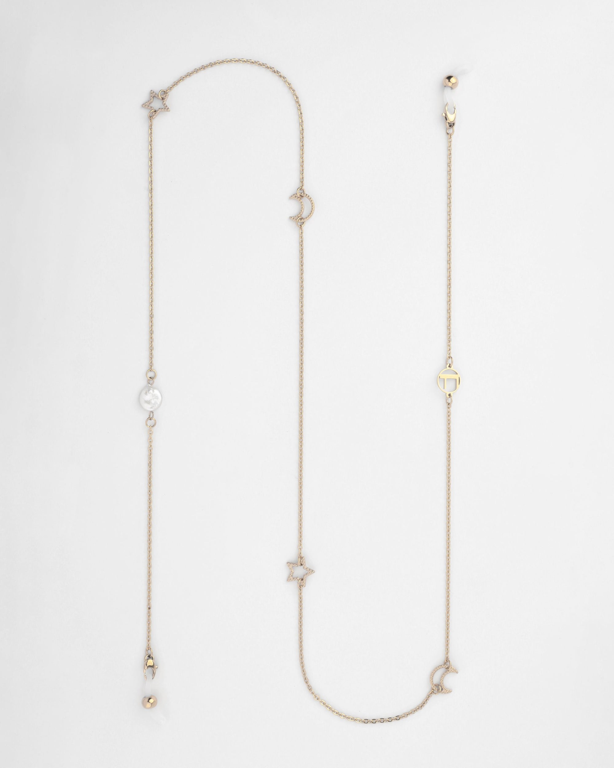 A Brixton Glasses Chain with a delicate, 18kt gold-plated chain featuring various charms including stars, moons, small round beads, and a freshwater pearl. The charms are spaced evenly, adding an elegant touch to the simple chain. The chain is laid out flat on a white background. This exquisite piece is crafted by For Art's Sake®.