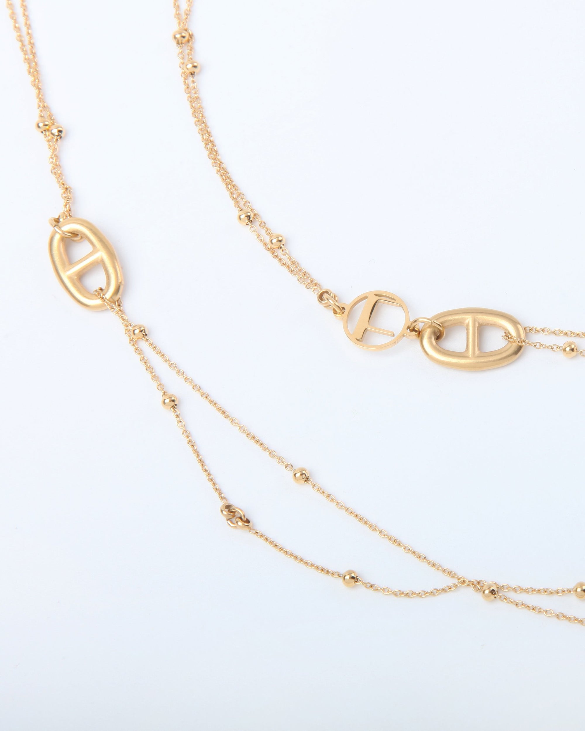 A close-up view of an elegant 18kt gold-plated Beetle Glasses Chain by For Art&#39;s Sake® with intricate chain details. The chain features small, oval-shaped, double-link pendants along its length, adding to its luxurious design. The background is a simple, solid white.