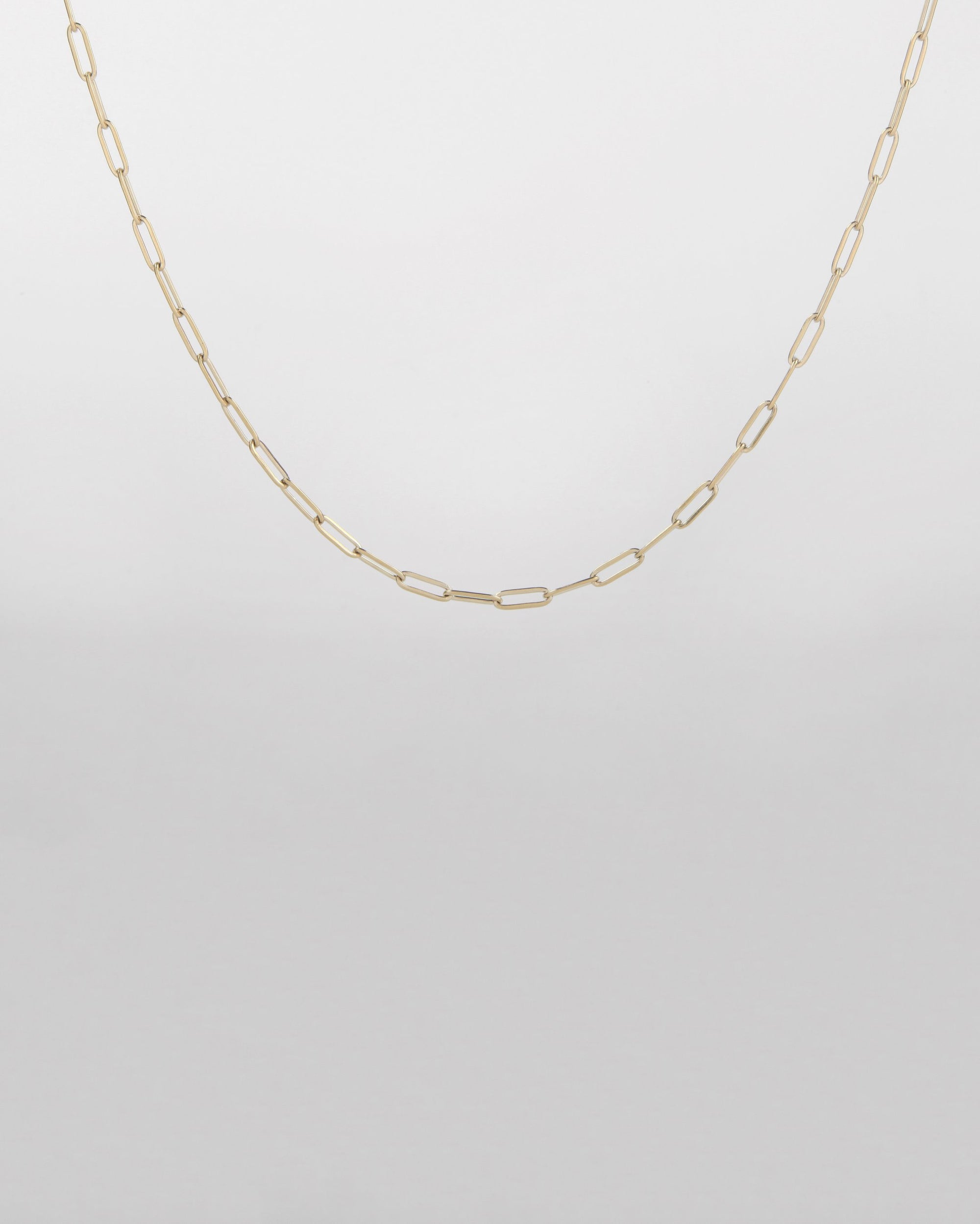 A delicate 18-karat gold-plated chain necklace with oval links is displayed against a plain white background. The simple yet elegant design highlights the thin, interconnected oval-shaped links, creating a minimalist and refined piece of jewelry. This is the Buddha Glasses Chain by For Art's Sake®.