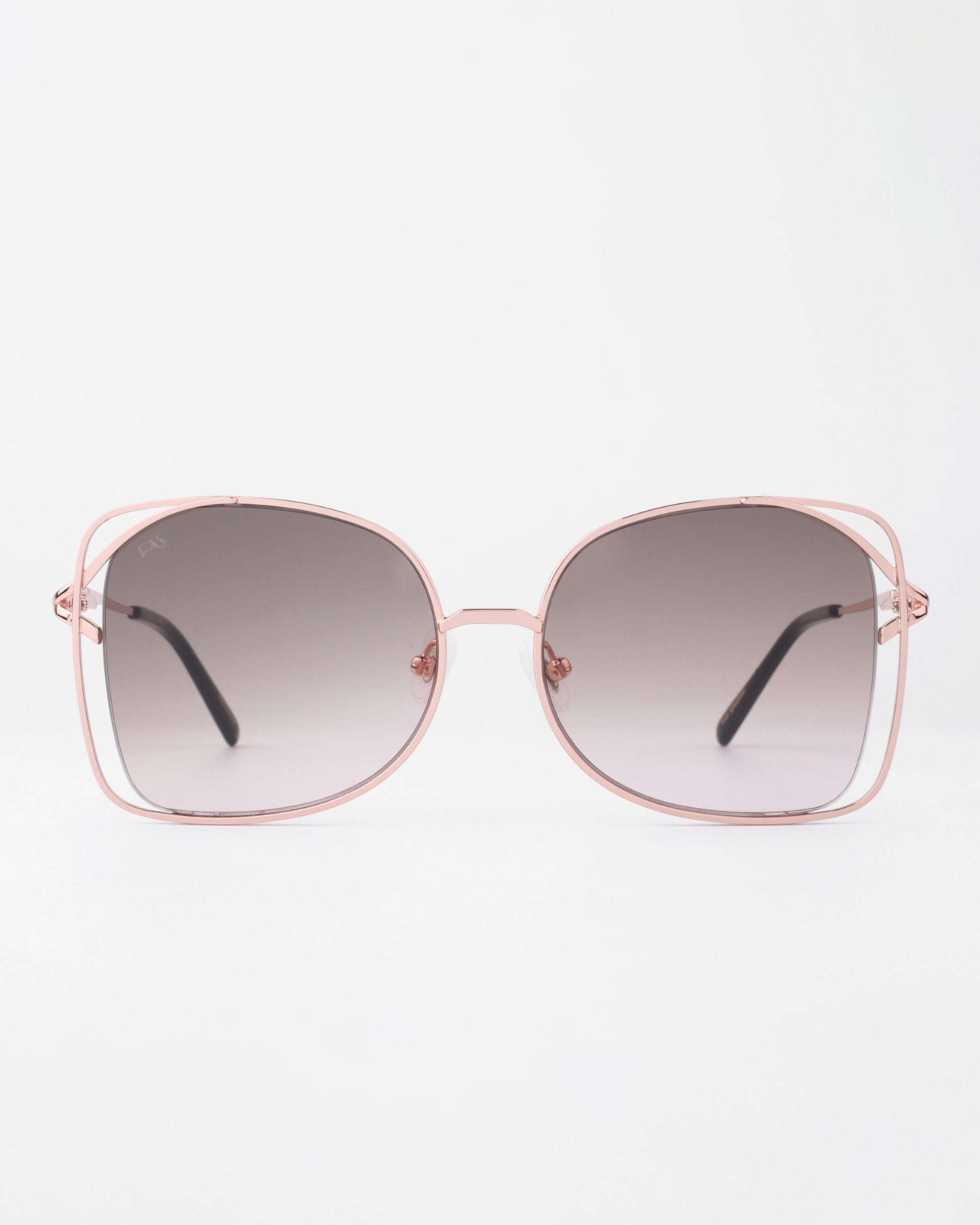 A pair of handmade, large, square-shaped Carousel sunglasses by For Art's Sake® with a thin, pink metal frame and gradient dark to light lenses. Crafted with gold-plated stainless steel for durability and style, they offer full UVA & UVB protection. The glasses are displayed against a plain white background with the temples extended outward.