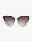 A pair of stylish cat-eye Venus sunglasses by For Art's Sake® with 18-karat gold plated frames and blue accents along the top. The nylon lenses are gradient, transitioning from dark at the top to lighter at the bottom. The sunglasses are placed against a plain white background.