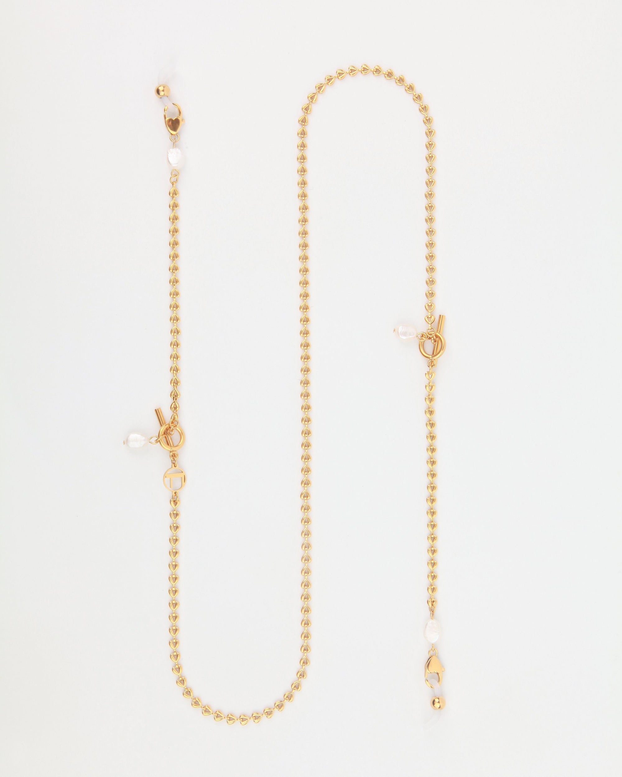 A delicate, 18-karat gold-plated Havana Glasses Chain with small, round beads and toggle clasps. The chain features freshwater pearl charms interspersed along the heart-shaped chain, giving it an elegant and sophisticated look. The design of the Havana Glasses Chain by For Art's Sake® is minimalist and refined.