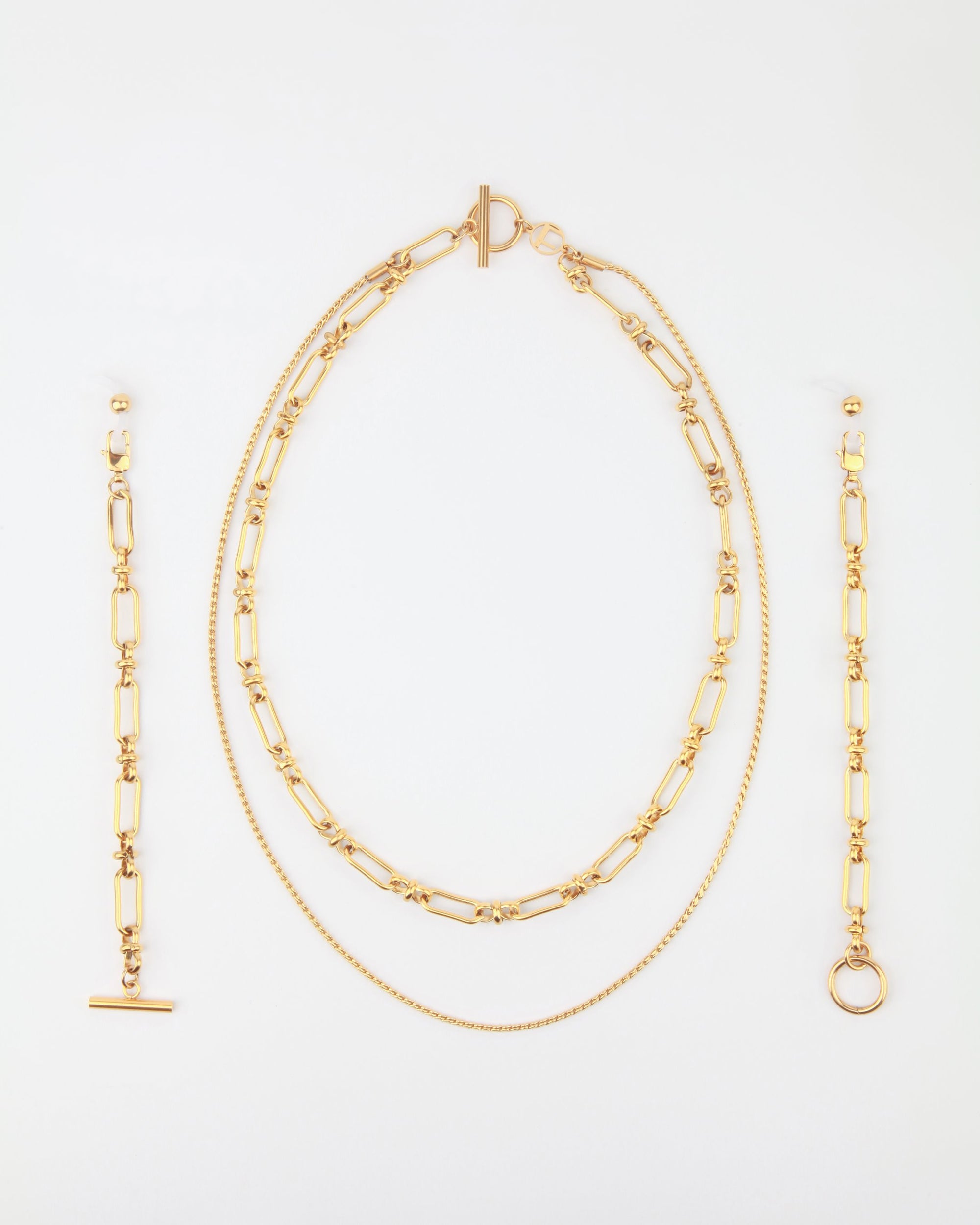 A Vienna Glasses Chain by For Art&#39;s Sake® against a white background, including a pair of dangling earrings, an 18-karat gold-plating layered necklace with both a chain and a linked design, and a bracelet featuring a similar linked pattern. The pieces are neatly arranged in a vertical orientation.