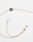 A delicate, lightweight chain in 18K gold features a small round tag inscribed with "Le Pompadour Limited" and is adorned with two freshwater pearl charms. The chain ends with a clasp for fastening, all set against a plain white background. Introducing the **Victoria Glasses Chain by For Art's Sake®**.