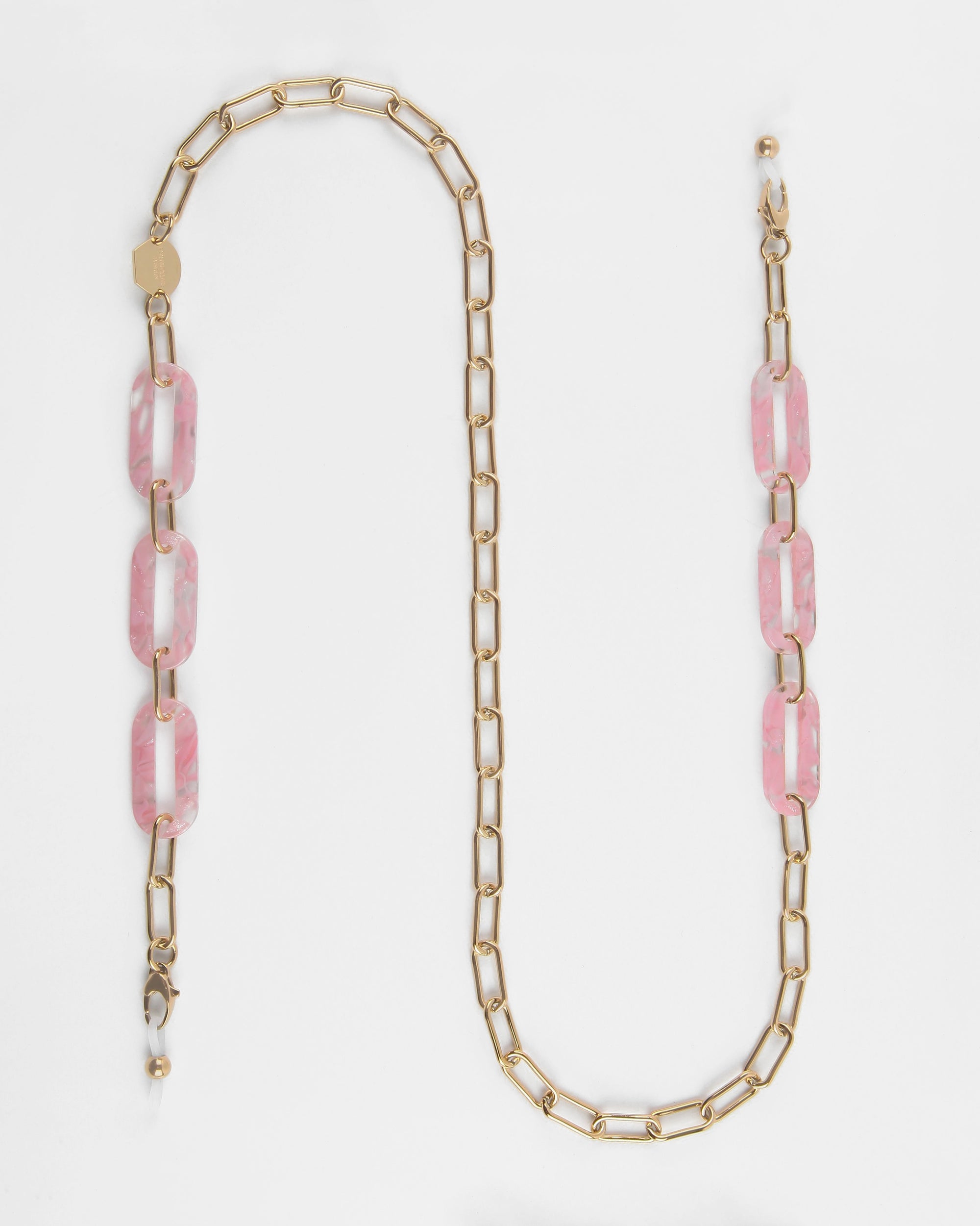 A long gold chain necklace called the Kensington Glasses Chain, made with 18-Karat gold by For Art&#39;s Sake®, features a series of rectangular links interspersed with larger, marbled pink and white resin links. The clasp is gold and the chain concludes with a small gold bead detail. The Kensington Glasses Chain is displayed on a white background.