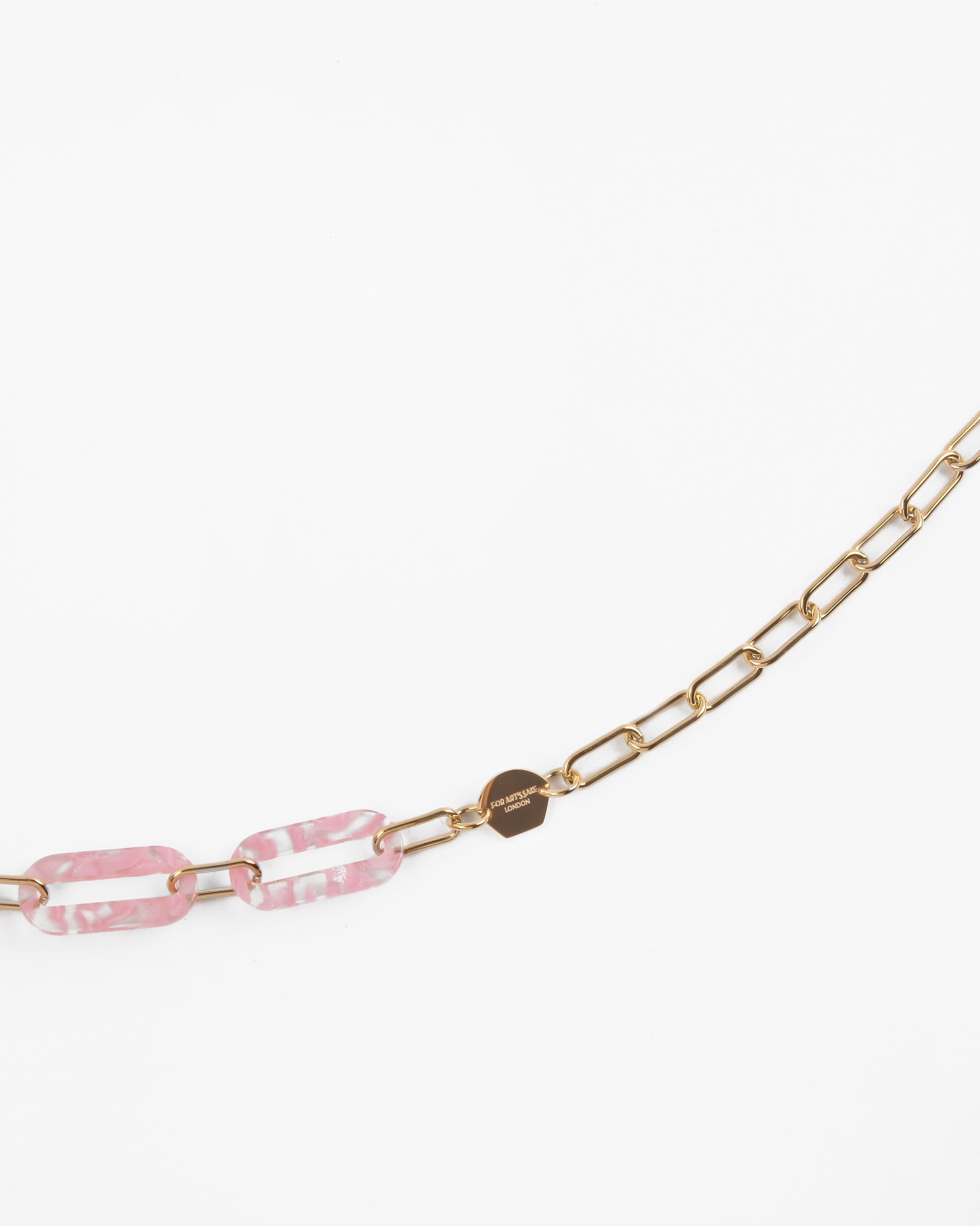 For Art&#39;s Sake® Kensington Glasses Chain with two elongated pink marbled links made from Italian acetate. A round 18-Karat gold tag is attached next to the pink links. The background is white.