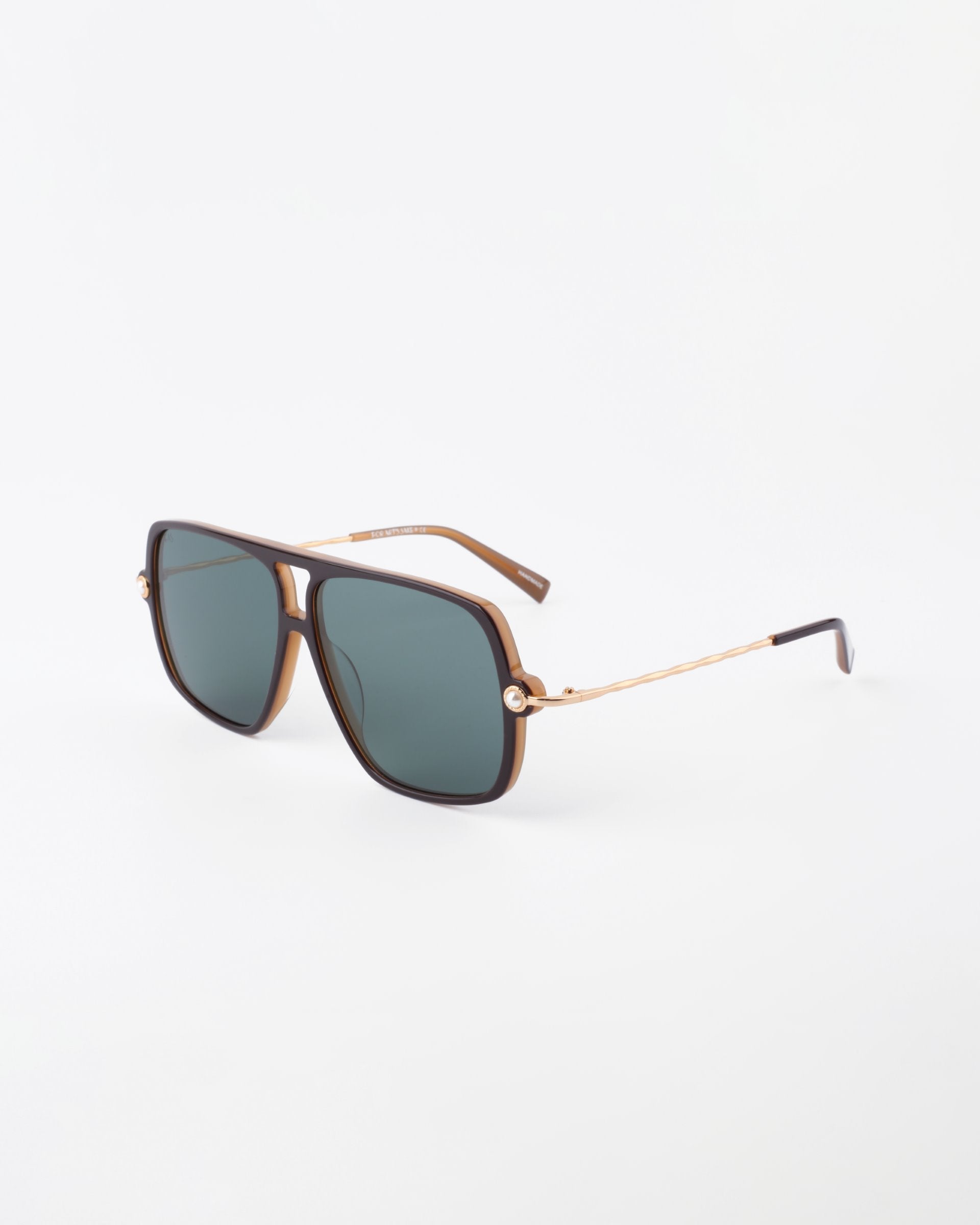 A pair of stylish For Art&#39;s Sake® Cinnamon sunglasses featuring a brown square frame with 18-karat gold-plated metal arms and dark tinted lenses. The sunglasses have a chic, modern design with a minimalist aesthetic. The background is plain white.