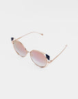 Introducing the Skylar sunglasses by For Art's Sake®—a pair of stylish, round, mirrored shades featuring elegant thin gold frames and dark blue accents on the earpiece tips. The lenses boast a subtle pinkish tint that reflects light with a captivating gradient effect. Don't miss your last chance to own these stunning Skylar shades, beautifully showcased against a plain white background.