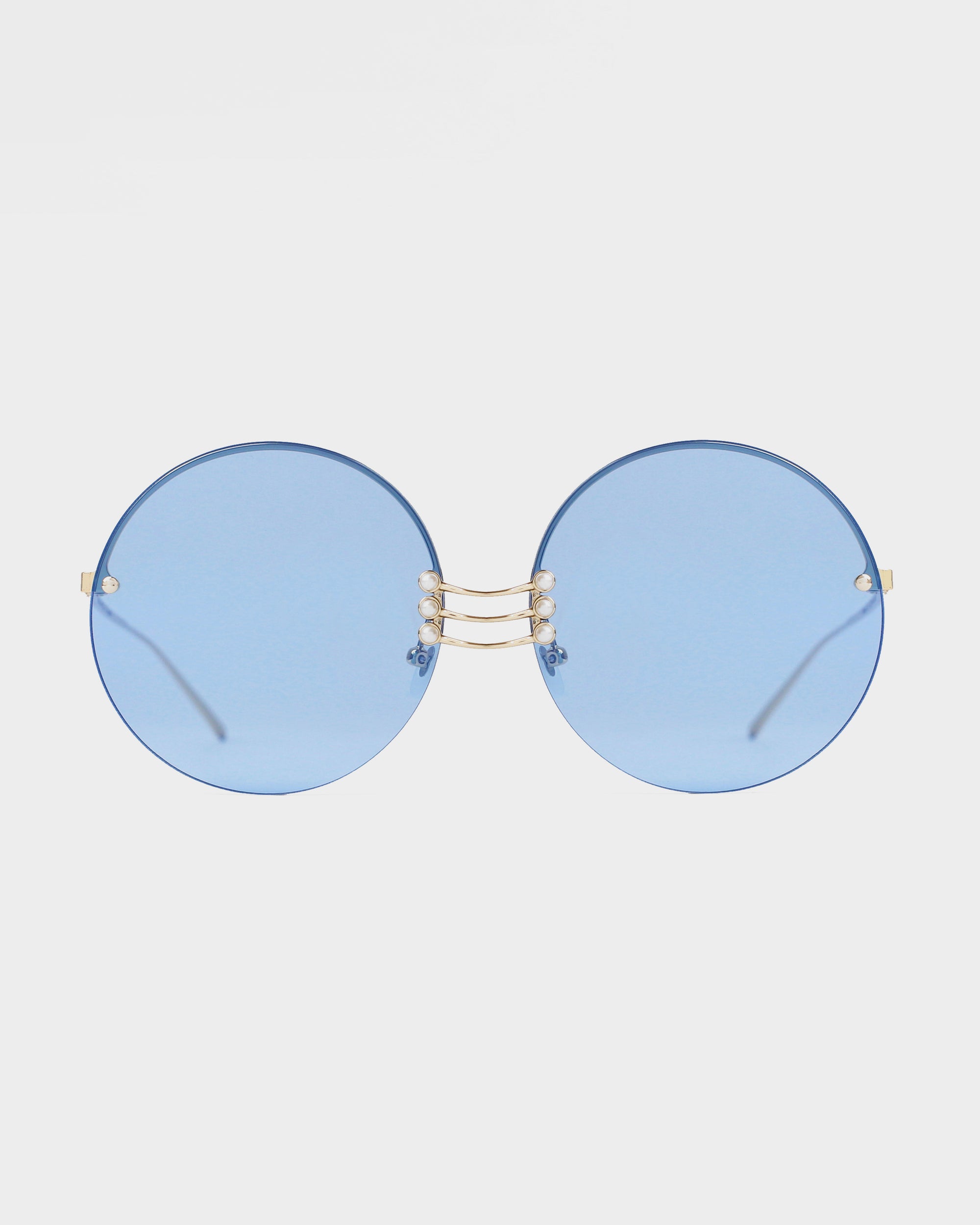 A pair of Vermeer sunglasses from For Art&#39;s Sake® with blue lenses and a thin gold metal frame. The bridge of the Vermeer sunglasses features two small connected bars, while the stainless steel frames ensure durability. The background is plain white, allowing the Vermeer sunglasses to be the focal point.