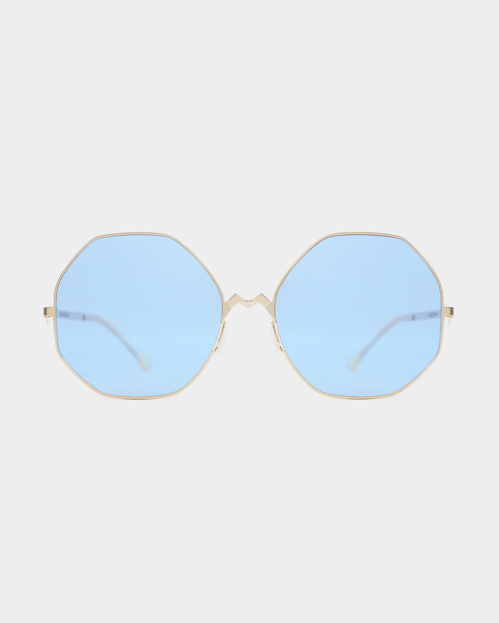 A pair of For Art&#39;s Sake® M8 sunglasses with gold-framed, octagon-shaped lenses in light blue tint, offering UV protection, shown against a plain white background.