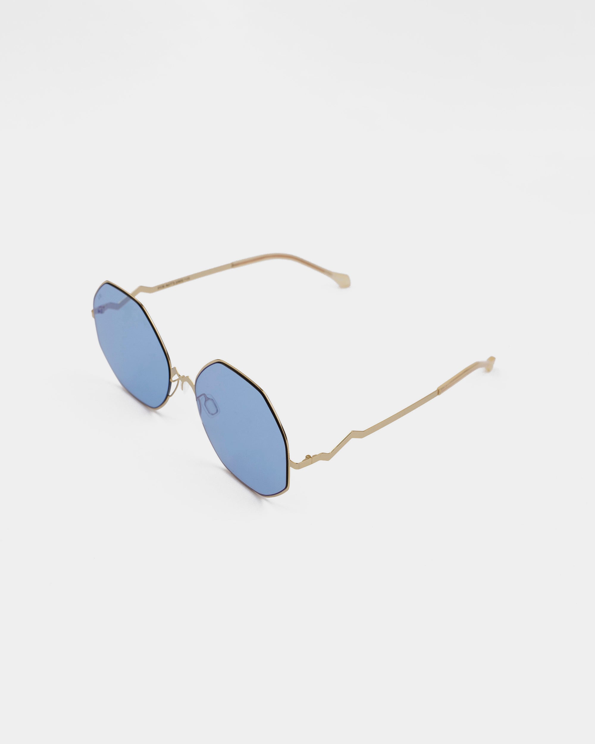 A pair of stylish For Art's Sake® M8 sunglasses featuring gold-colored stainless steel frames and blue-tinted lenses with UV protection. The thin, curved arms have a slight bend at the tips for a secure fit. The white background highlights the elegance of these sunglasses.