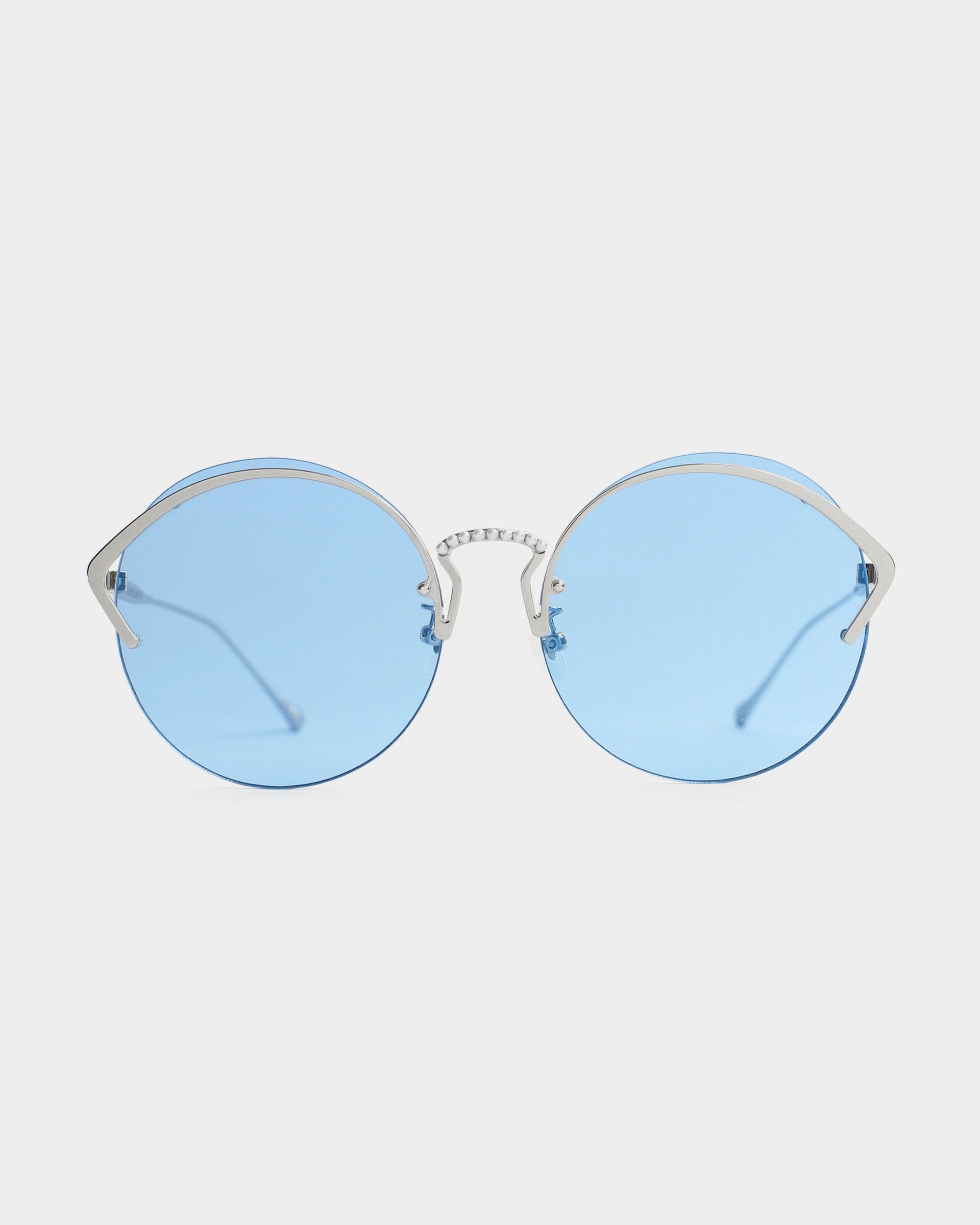 Round sunglasses with thin stainless steel frames and light blue Nylon lenses, set against a plain white background. The bridge features a subtle textured design, offering both style and UV protection. These are the Margarita sunglasses by For Art&#39;s Sake®.