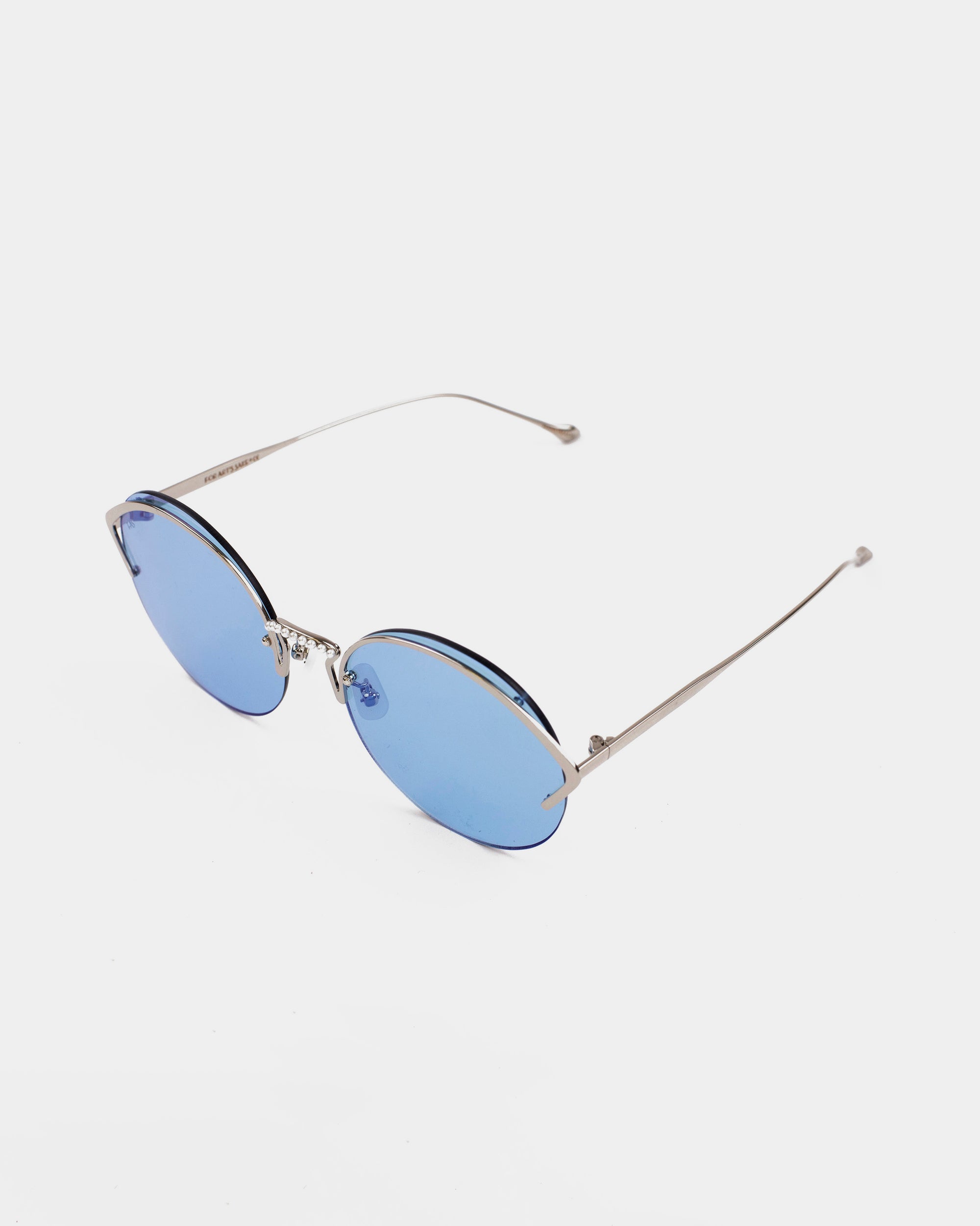 A pair of For Art&#39;s Sake® Margarita sunglasses with blue-tinted nylon lenses and thin stainless steel frames and arms, boasting UV protection, set against a plain white background.