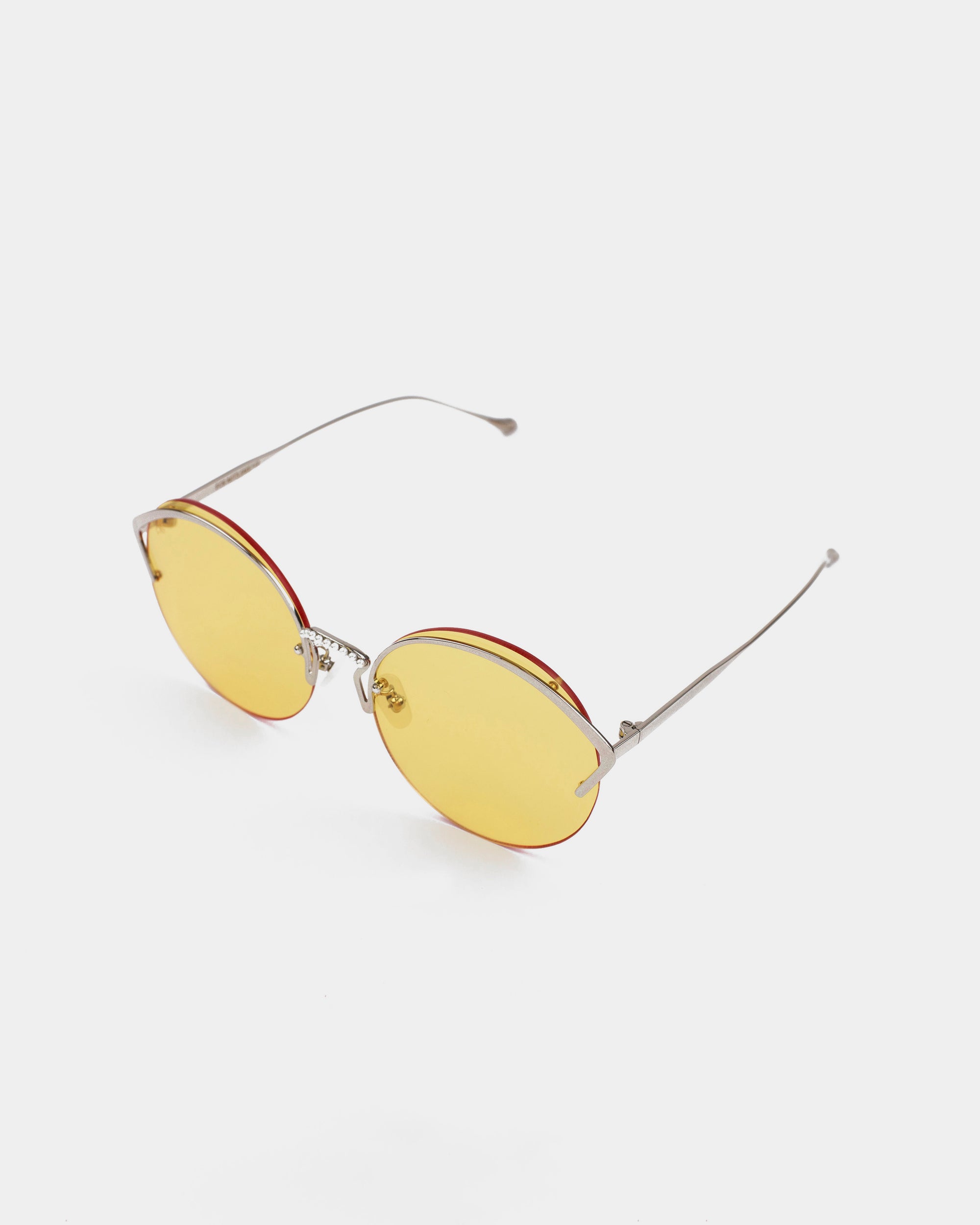 A pair of modern **Margarita** sunglasses by **For Art&#39;s Sake®** with oval-shaped yellow nylon lenses, thin stainless steel frames, and red accents around the lenses. The sunglasses, offering UV protection, are placed on a plain white background, tilted slightly to the left.