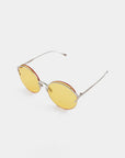 A pair of modern **Margarita** sunglasses by **For Art's Sake®** with oval-shaped yellow nylon lenses, thin stainless steel frames, and red accents around the lenses. The sunglasses, offering UV protection, are placed on a plain white background, tilted slightly to the left.