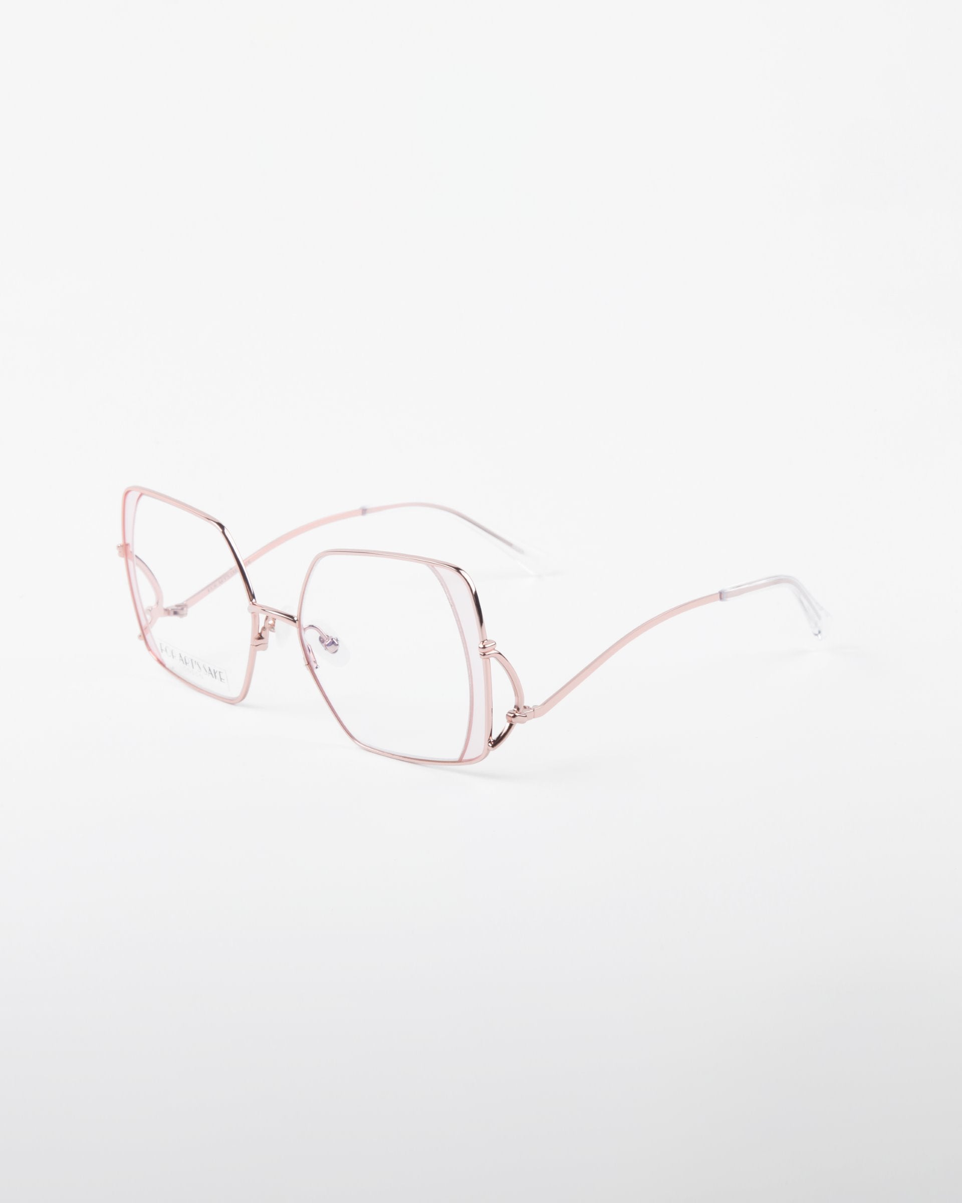 A pair of stainless steel eyeglasses with thin, pale pink metal frames. The lenses are hexagonal in shape, and the temples are also a matching pink with transparent ends. Perfect for prescription services or adding a blue light filter. The background is plain white. These eyeglasses are called &quot;Candy&quot; by For Art&#39;s Sake®.