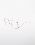 A pair of stainless steel eyeglasses with thin, pale pink metal frames. The lenses are hexagonal in shape, and the temples are also a matching pink with transparent ends. Perfect for prescription services or adding a blue light filter. The background is plain white. These eyeglasses are called "Candy" by For Art's Sake®.