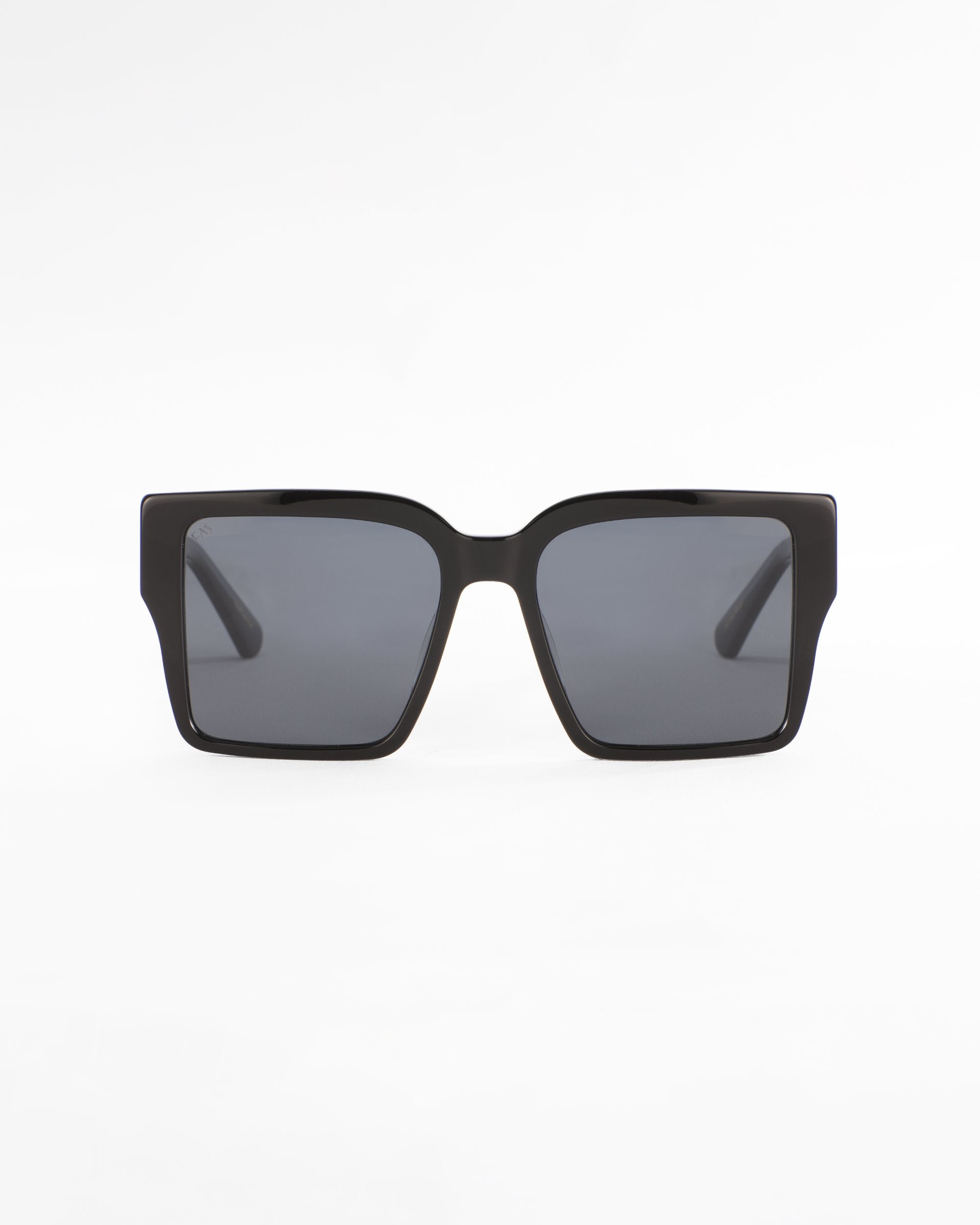 A pair of black rectangular For Art&#39;s Sake® Castle sunglasses with ultra-lightweight lenses is centered against a plain white background. The frames have a simple, modern design with slightly rounded edges.