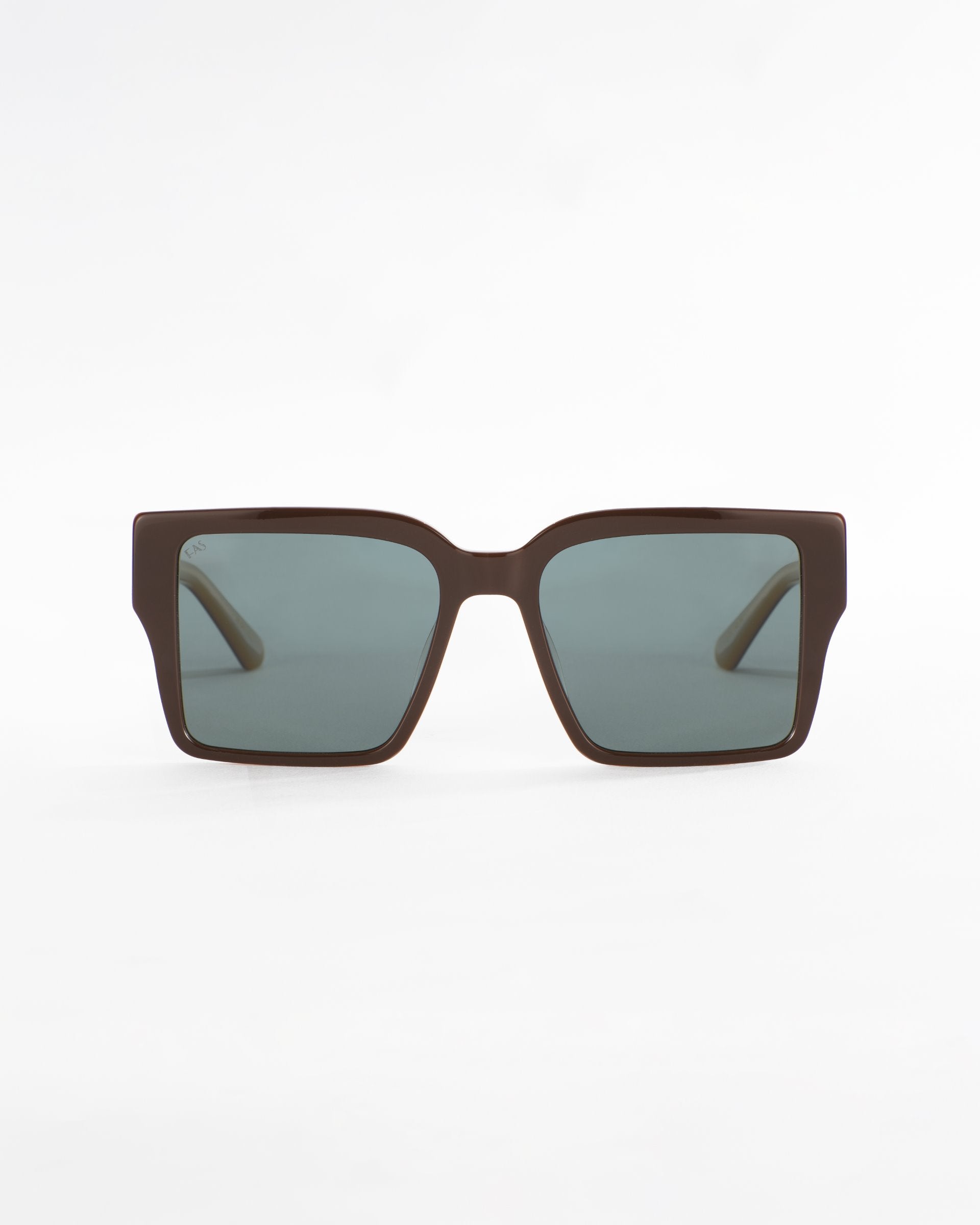 A pair of dark brown, oversized square-framed For Art's Sake® Castle sunglasses with ultra-lightweight green-tinted lenses displayed against a plain white background. The design is modern and sleek, with wide arms for a bold look.