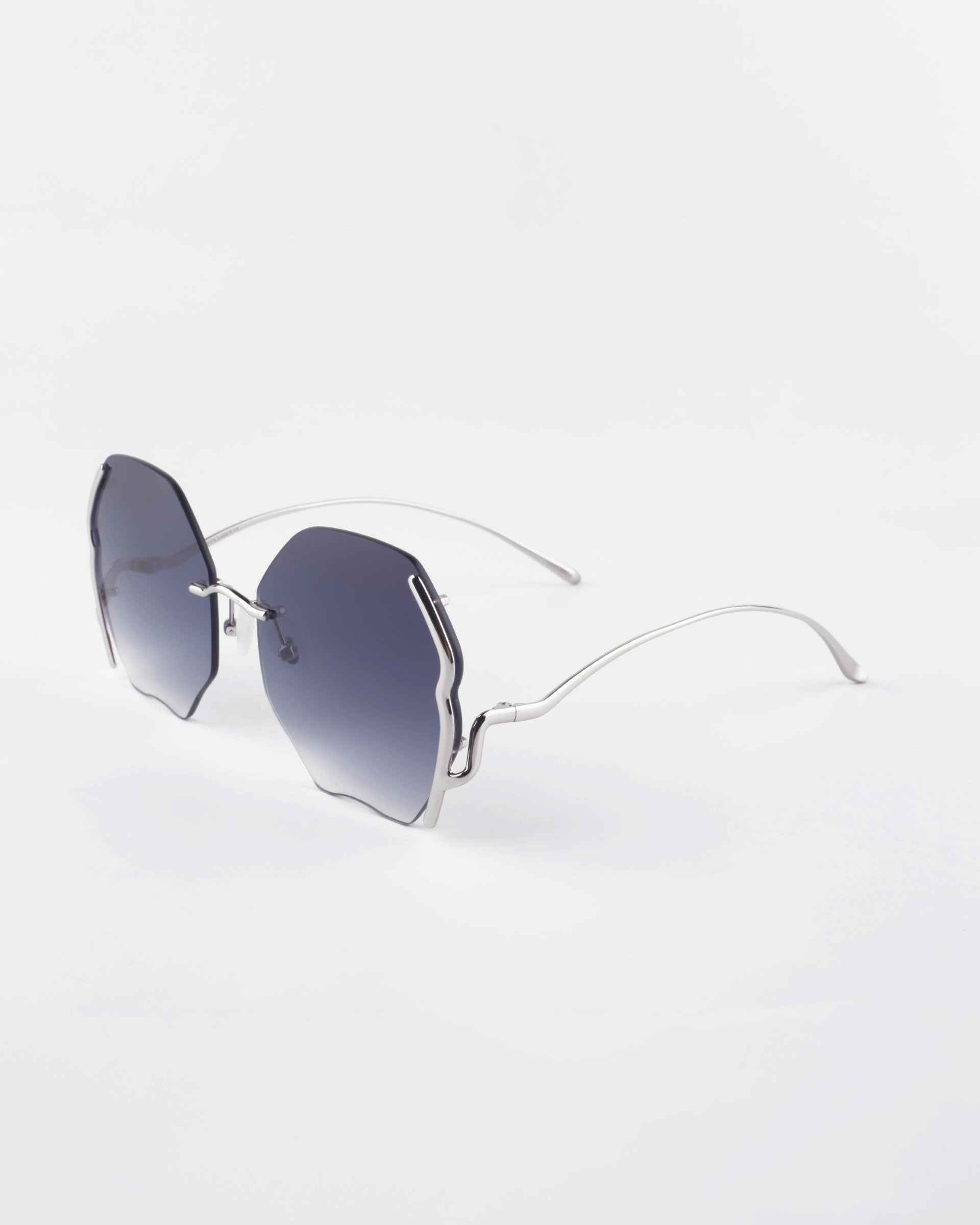 Fashionable Art Deco Century sunglasses by For Art’s Sake® with uniquely shaped, frameless dark lenses and sleek, curved gold-plated stainless steel temples placed against a white background.