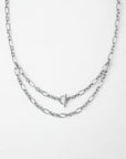 A Clio Glasses Chain from For Art's Sake® with two layers of links is pictured on a white background. The chain features a T-bar clasp positioned at the front, adding a subtle decorative element. The links vary slightly in size, creating a delicate yet intricate design characteristic of layered chains.