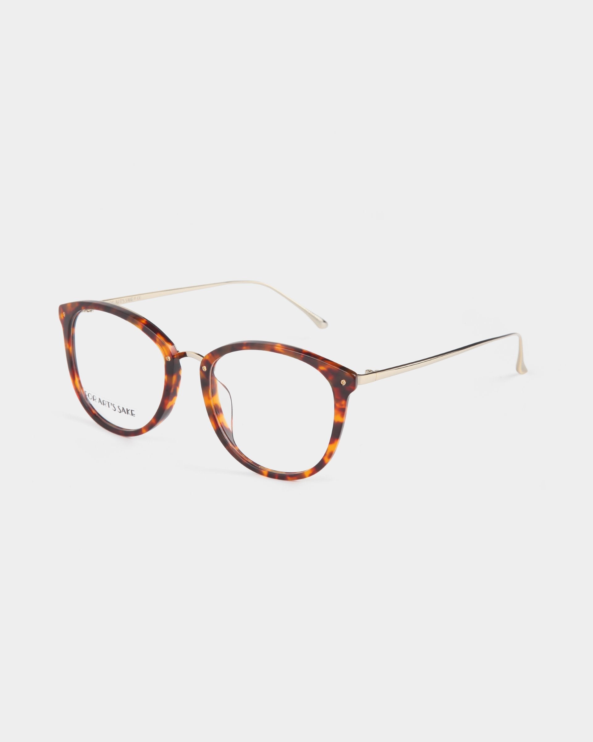 A pair of Club Brown glasses by For Art's Sake® with a tortoiseshell-pattern and a rounded cat-eye shape. The lenses are clear, featuring an optional blue light filter, and the thin gold temples and nose pads provide a lightweight and elegant design. Offered with a prescription service, these opticals are set against a plain white background.