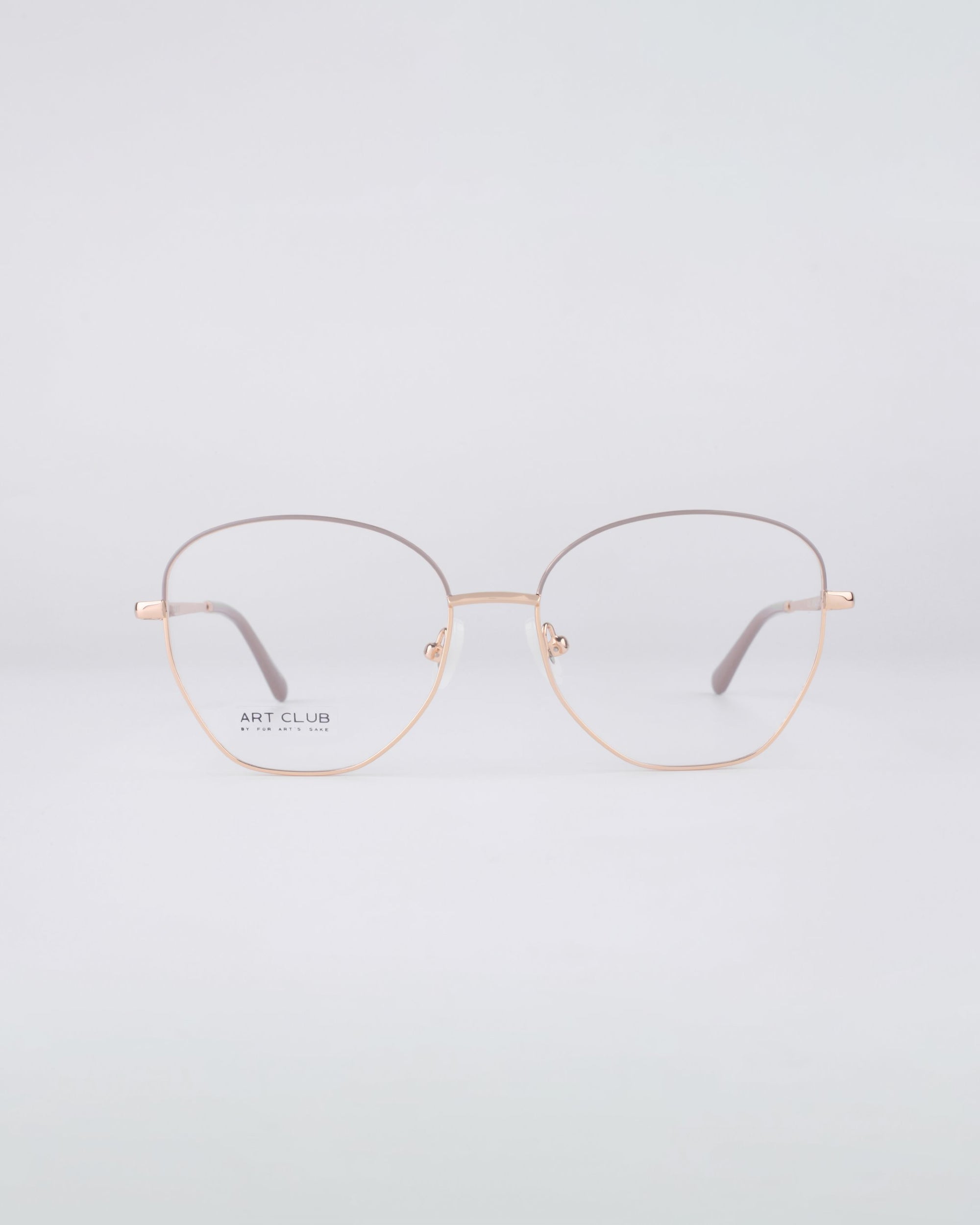 A pair of minimalist Coco eyeglasses by For Art's Sake® features thin, round gold contours and is showcased against a light gray background. The lightweight stainless steel construction and blue light filter lenses create a subtle reflection, with a small logo visible on the left lens.