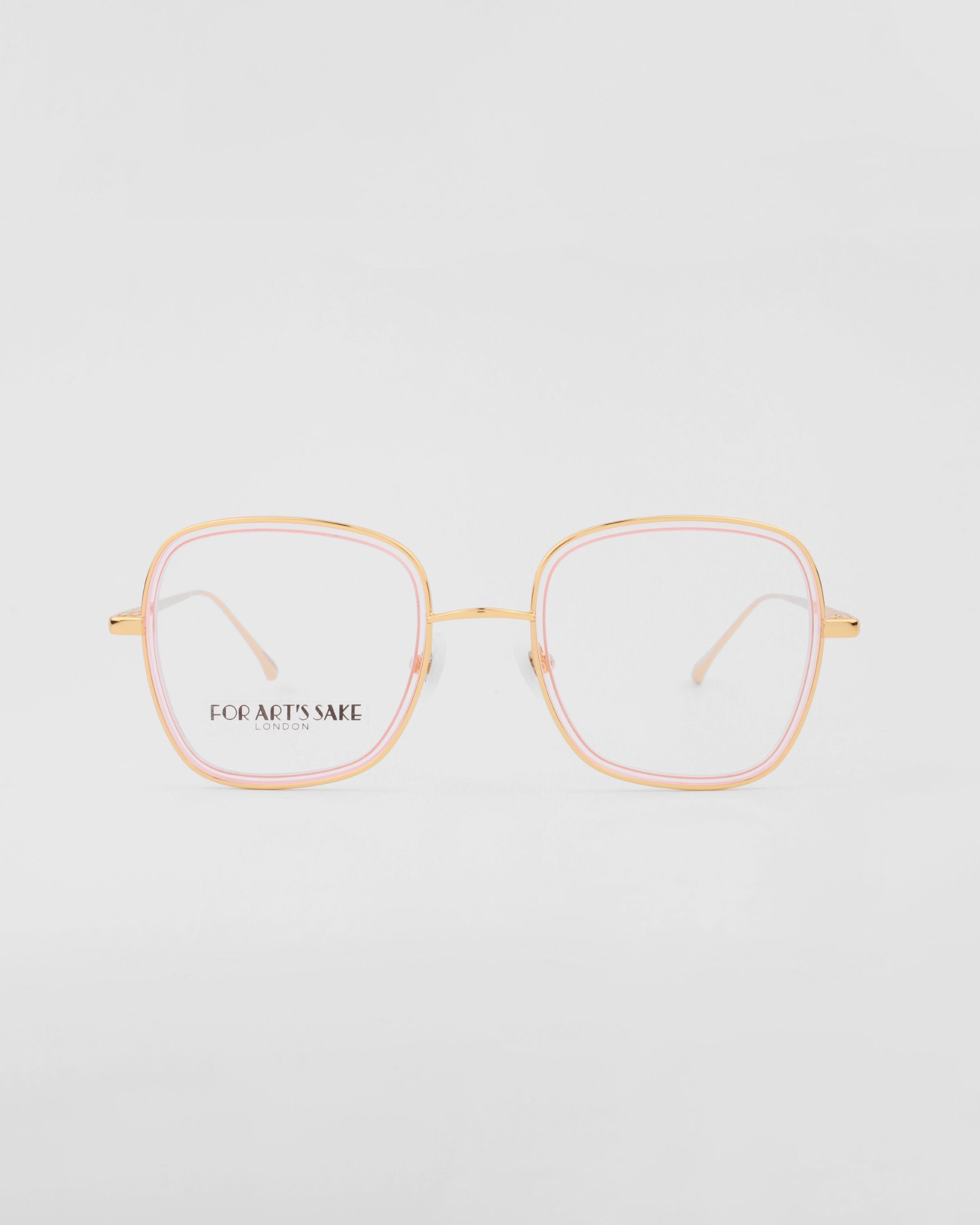 A pair of eyeglasses with thin, 18-karat gold-plated frames and a hint of pink detailing around the rims. The shape of the lenses is a rounded square, equipped with a blue light filter. The brand "For Art's Sake®" is printed on the left lens. The background is white. This stylish accessory is named Coconut by For Art's Sake®.