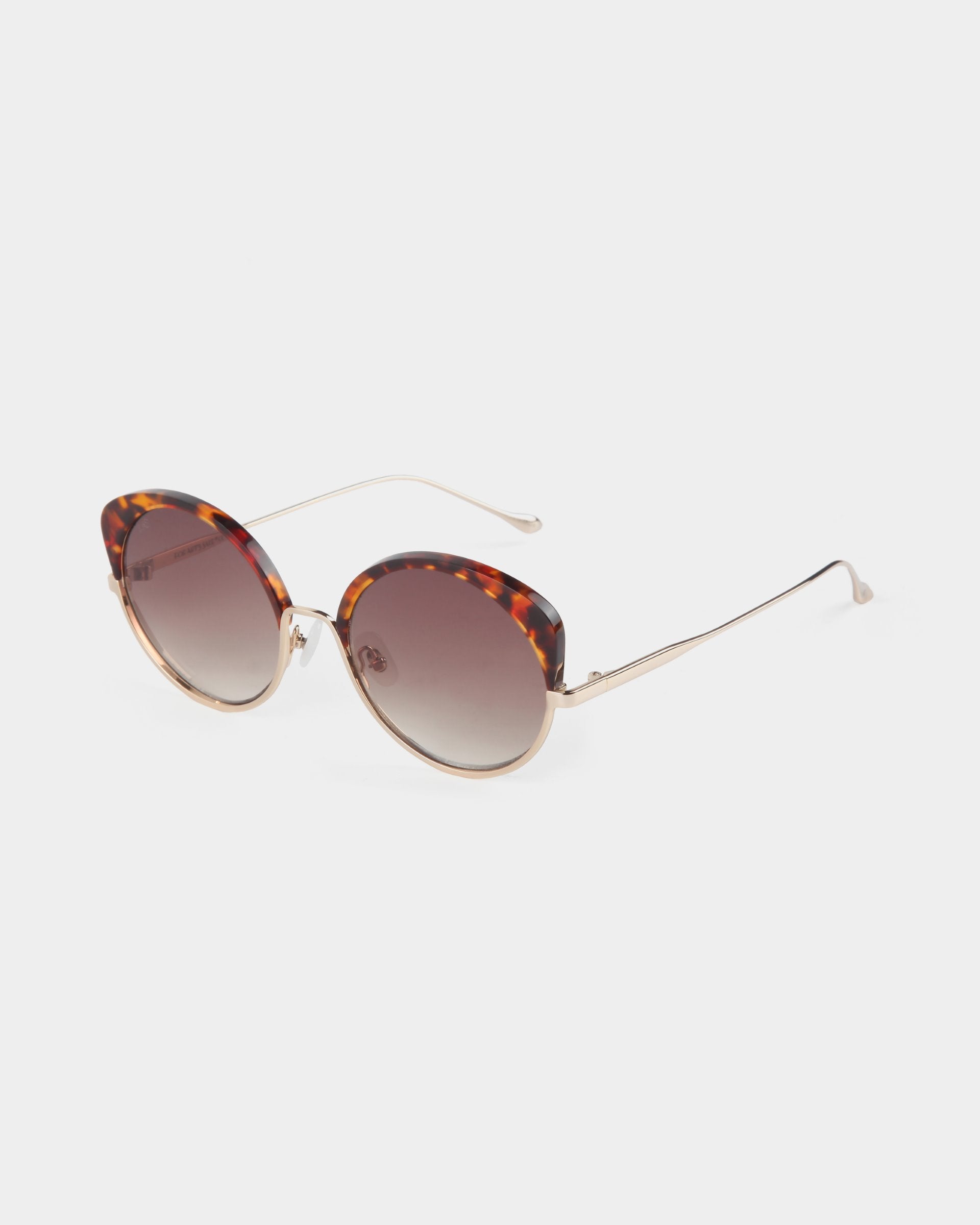 Cocoon by For Art&#39;s Sake®: Cat-eye sunglasses with tortoiseshell pattern on the upper frame and temples, featuring gold metal arms and gradient brown lenses, offering UV protection, set against a plain white background.