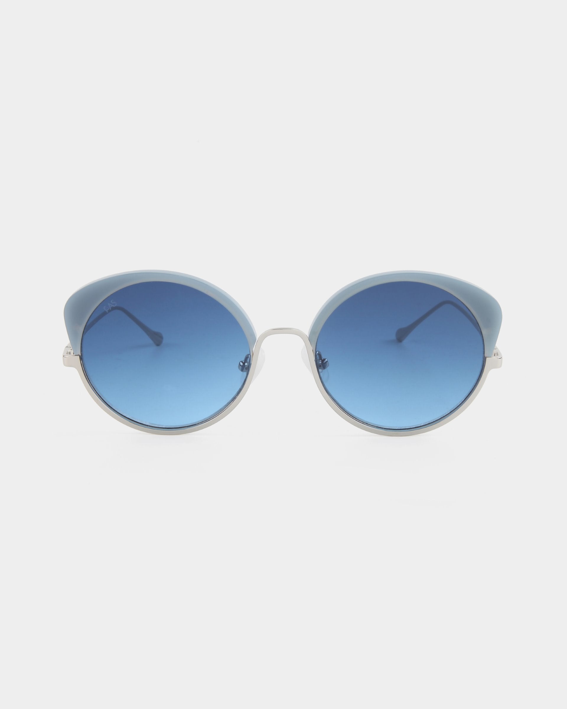 A pair of round, blue-tinted Cocoon sunglasses by For Art&#39;s Sake® with thin metallic frames and light blue to clear gradient lenses, viewed from the front against a plain white background. This handcrafted eyewear not only exudes elegance but also offers UV protection for your eyes.