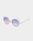A pair of stylish, handcrafted Cocoon cat-eye sunglasses by For Art's Sake® with light purple frames and rose gold temples. The lenses are round with a gradient tint that transitions from purple to clear, offering essential UV protection. The Cocoon sunglasses by For Art's Sake® rest elegantly on a white surface.
