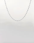 A delicate, thin silver Coral Glasses Chain by For Art's Sake® is displayed against a plain white background. The chain has small, evenly spaced links, creating a minimalist and elegant design, reminiscent of the finesse seen in eyewear chains.