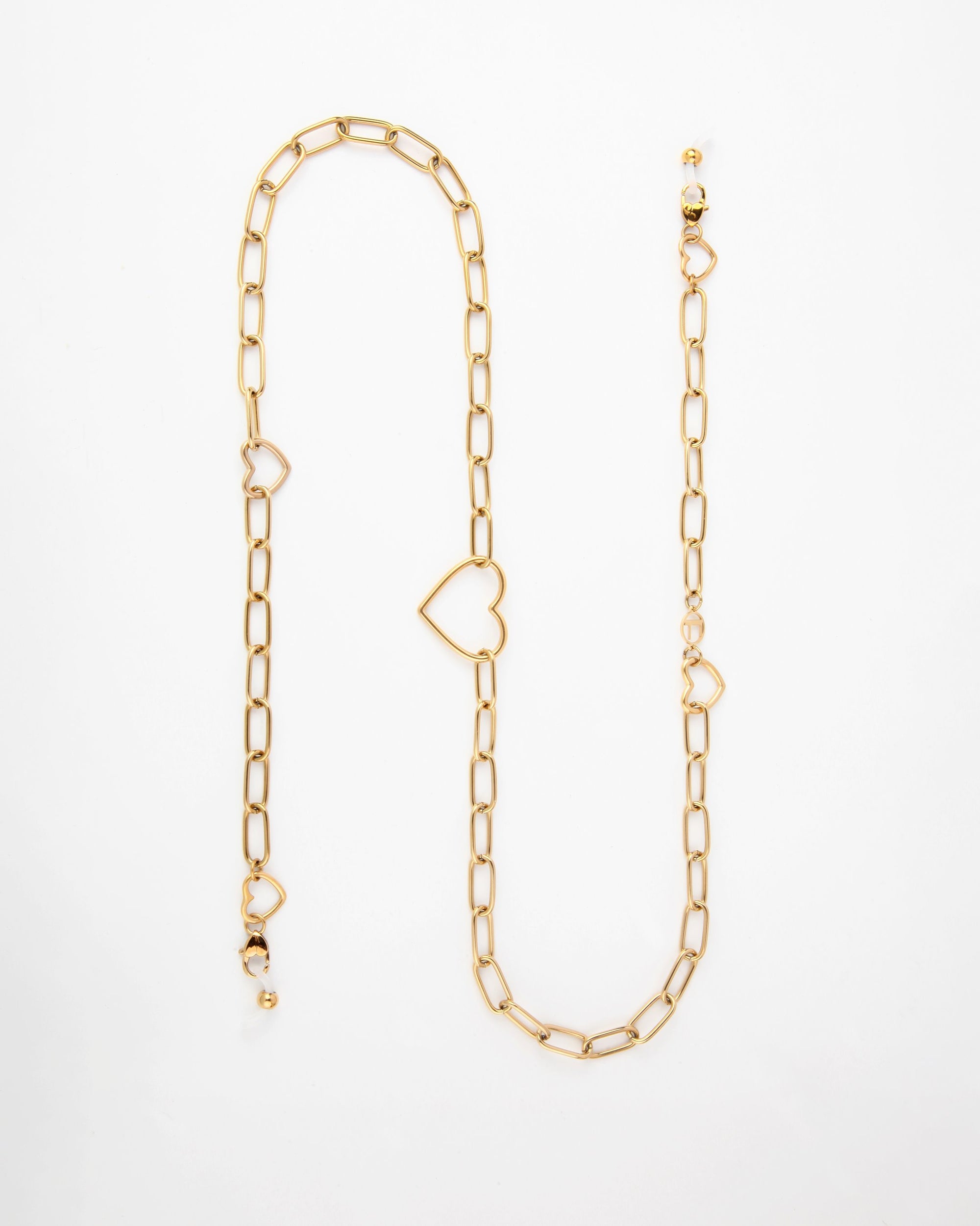 A gold chain-link necklace featuring two heart-shaped links and several small bead accents, this 18K gold-plated Cupid Glasses Chain by For Art's Sake® is laid out in an elongated, slightly curved manner on a white background.