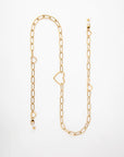 A gold chain-link necklace featuring two heart-shaped links and several small bead accents, this 18K gold-plated Cupid Glasses Chain by For Art's Sake® is laid out in an elongated, slightly curved manner on a white background.