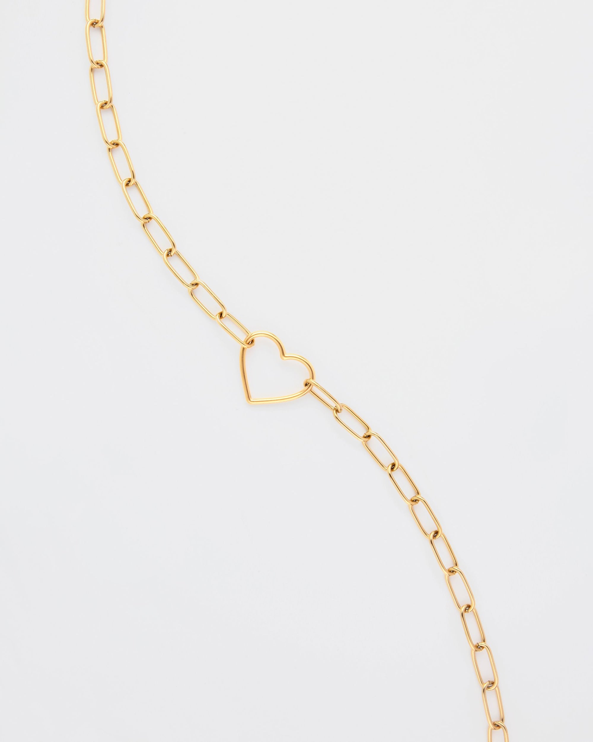 A delicate For Art's Sake® Cupid Glasses Chain with elongated links and a small, open-heart pendant at its center, displayed against a white background. The minimalist design features the heart shape as the focal point.